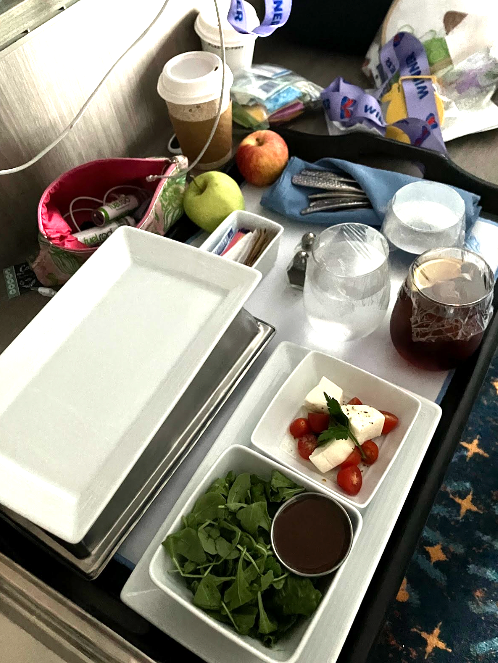 Hotel country   work  tray with salad, tomatoes, cheese, tea, and coffee. Nearby are an apple, portion  cups, and idiosyncratic   items connected  the table