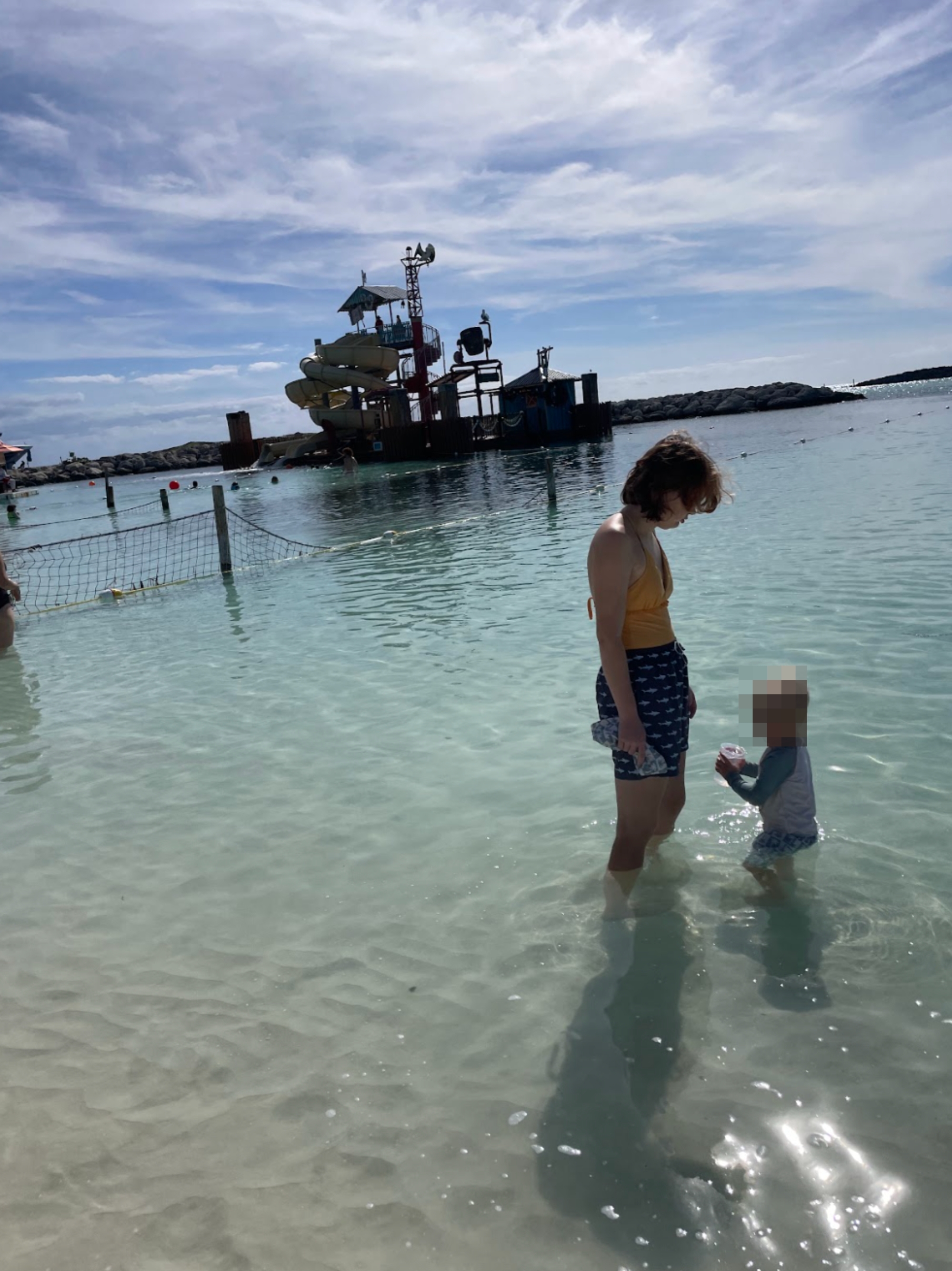 Person stands successful  shallow h2o  with kid  adjacent   a beachside playground, engaging successful  a playful moment