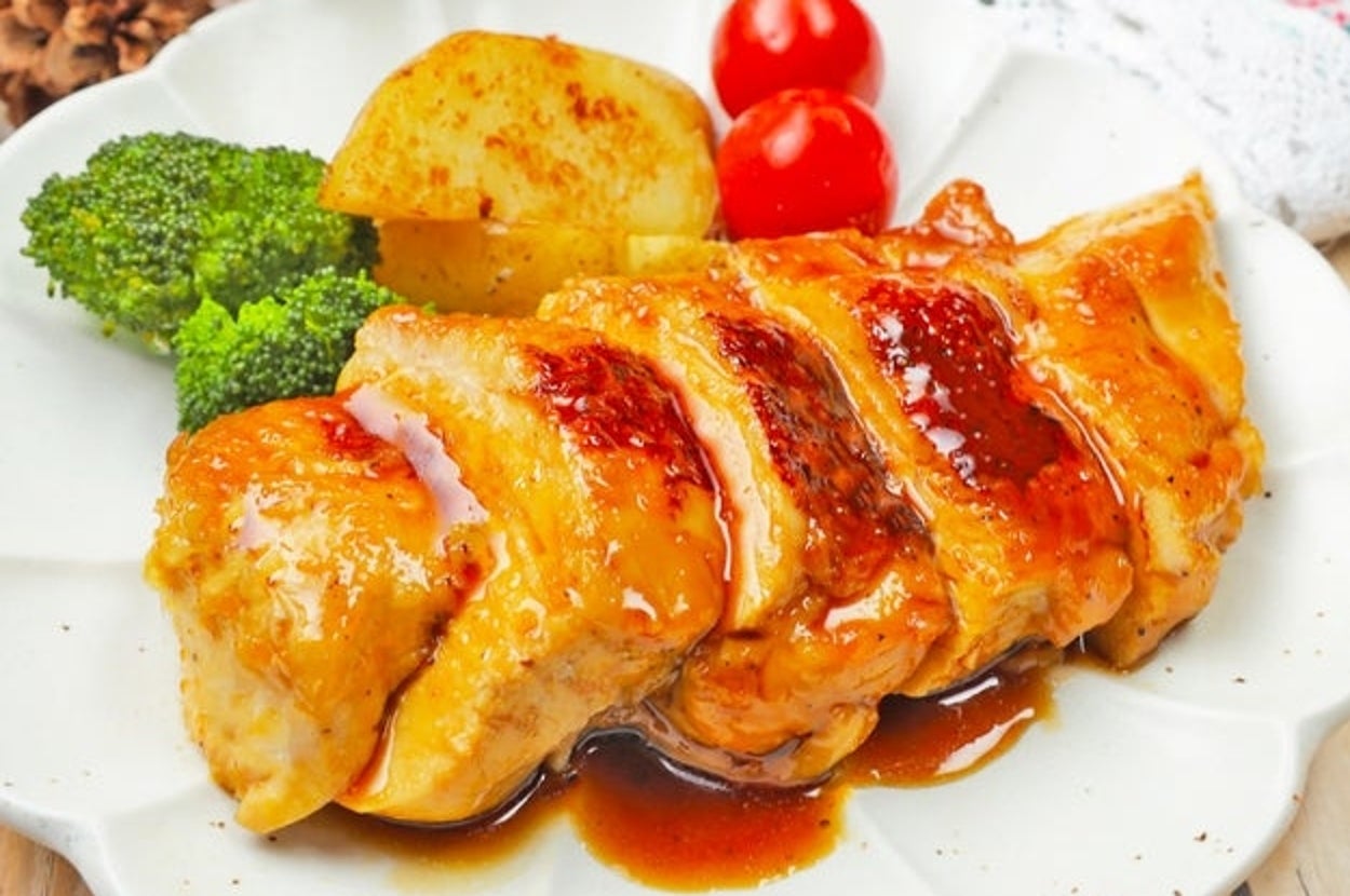 グリルチキンに艶やかなソースがかかり、ブロッコリー、ポテト、トマトが添えられた料理が白い皿に盛り付けられている。