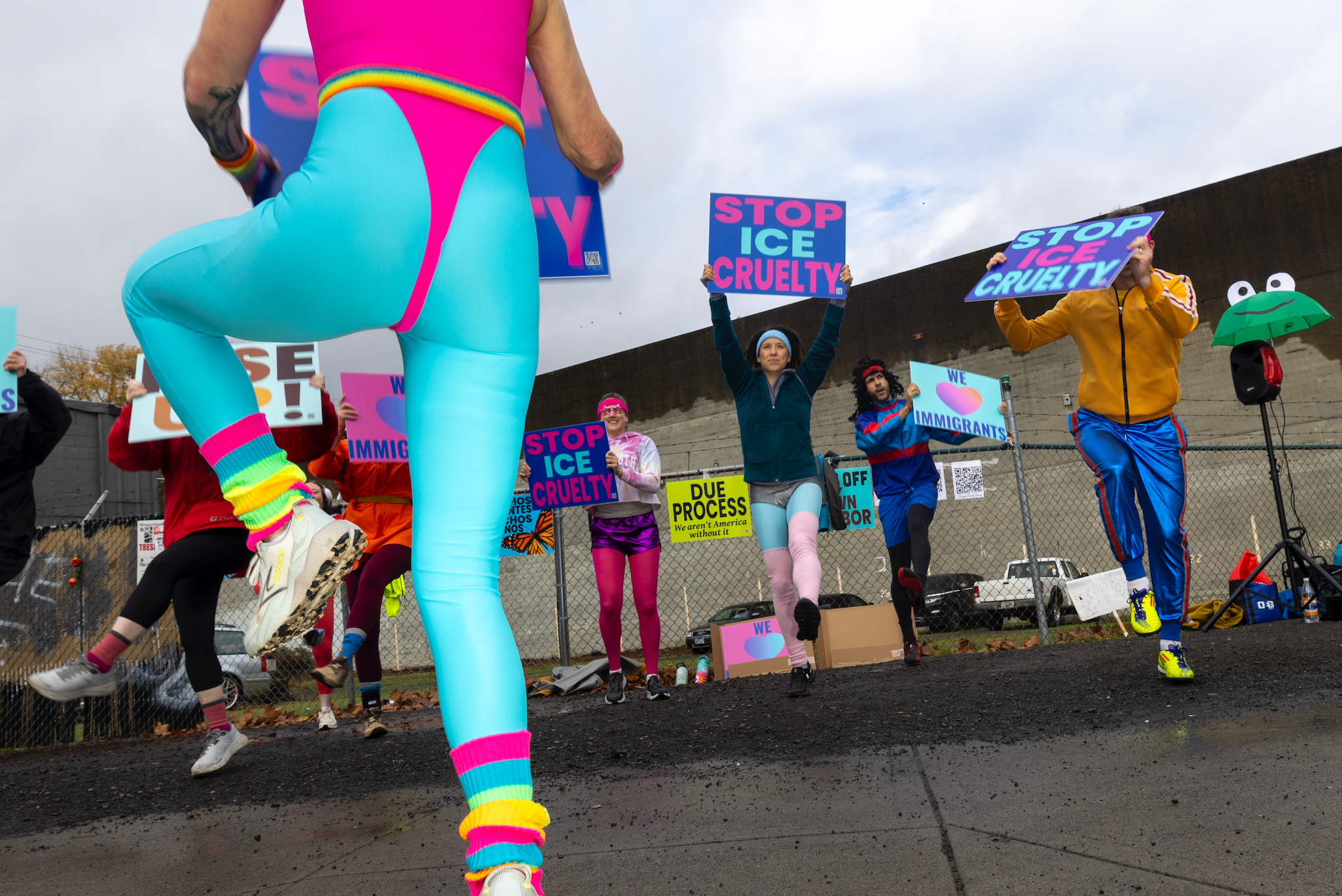 People successful bold, colorful outfits protest, holding "Stop ICE Cruelty" signs. They are cheerfully engaged successful a demonstration