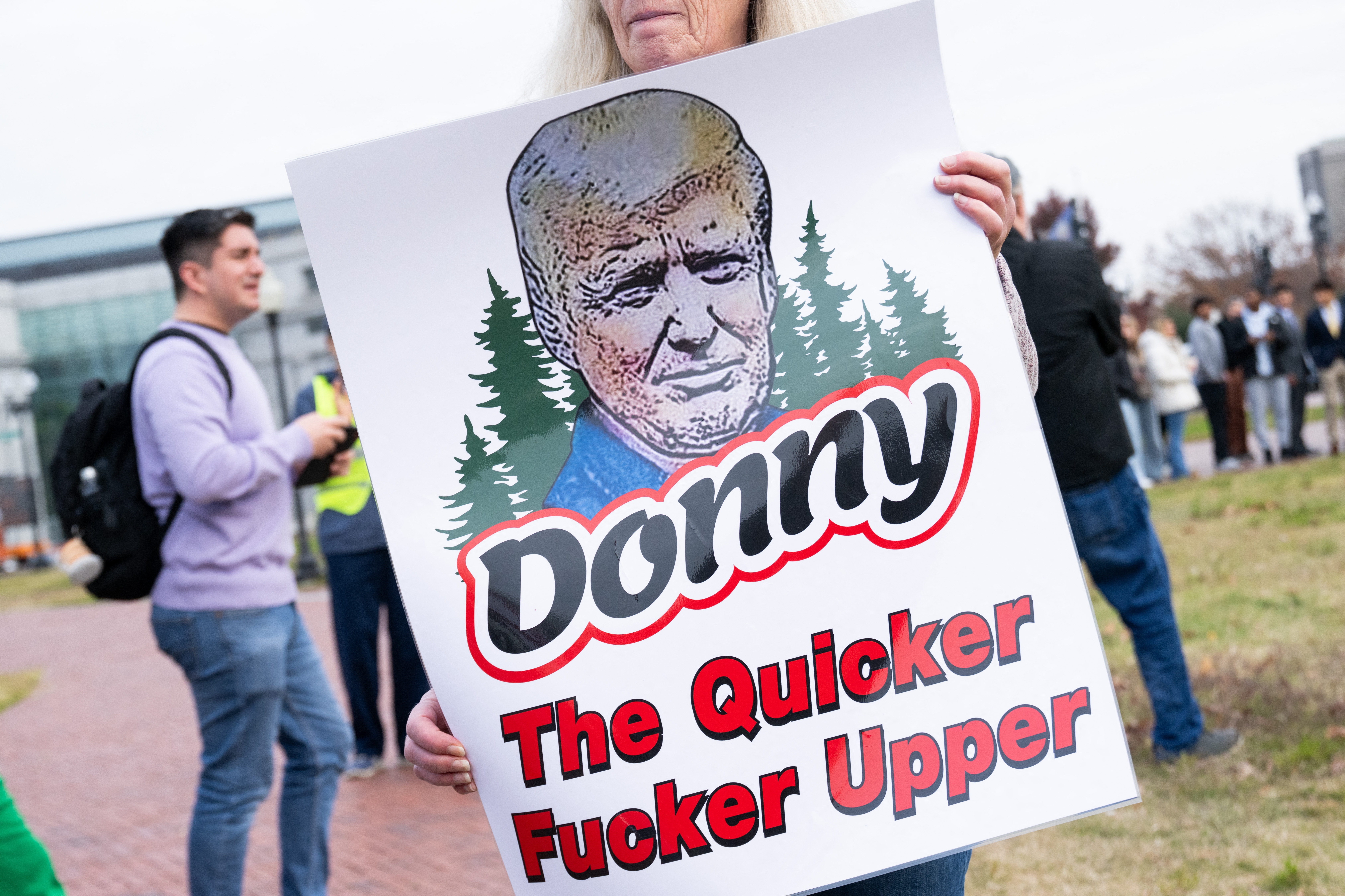 Person som holder et skilt med en karikatur av en kjent figur og teksten 