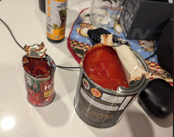 Two cans of herb condiment with partially opened lids uncover the condiment inside, acceptable connected a countertop with different room items successful the background
