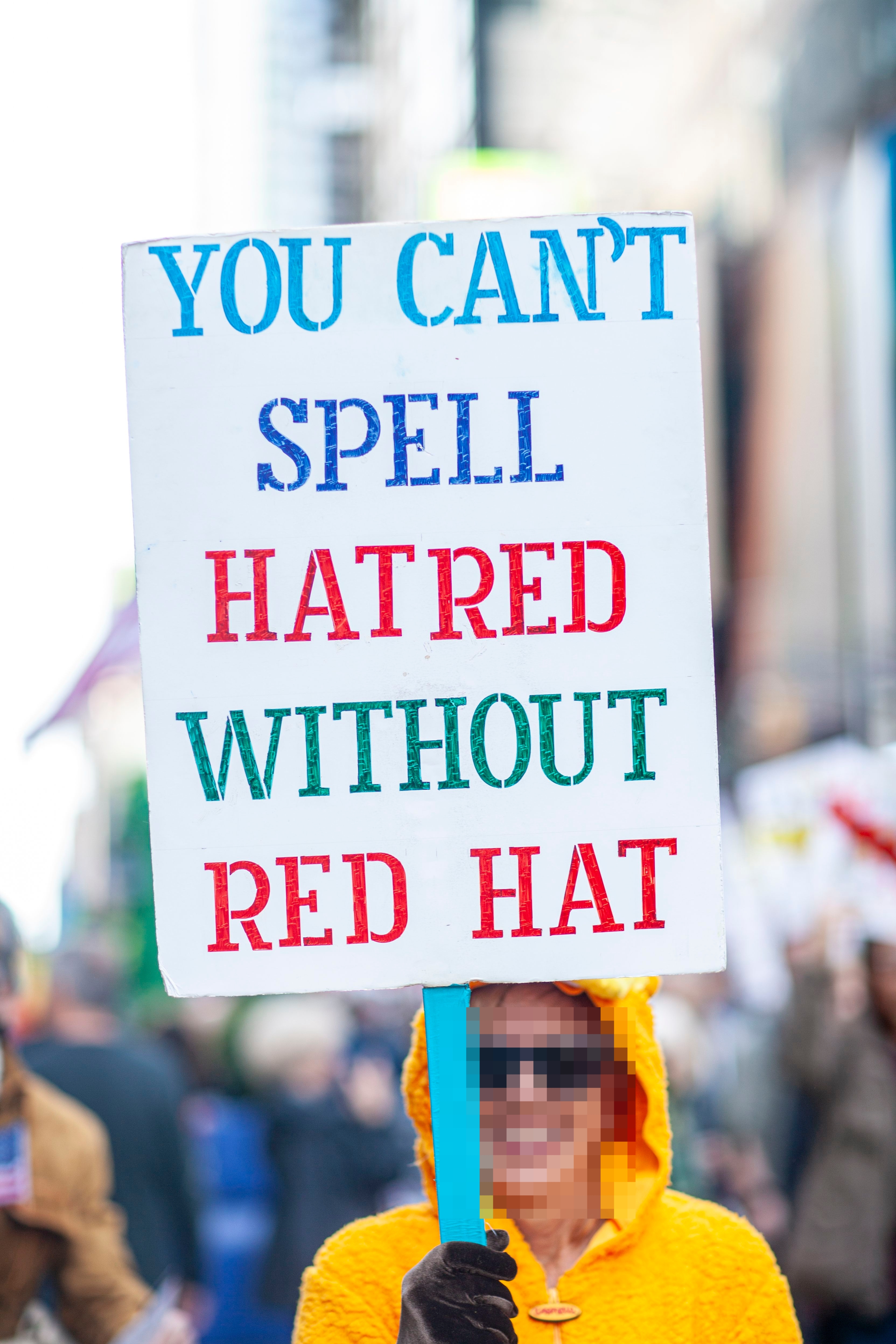 Person i en folkemengde som holder et skilt med teksten 