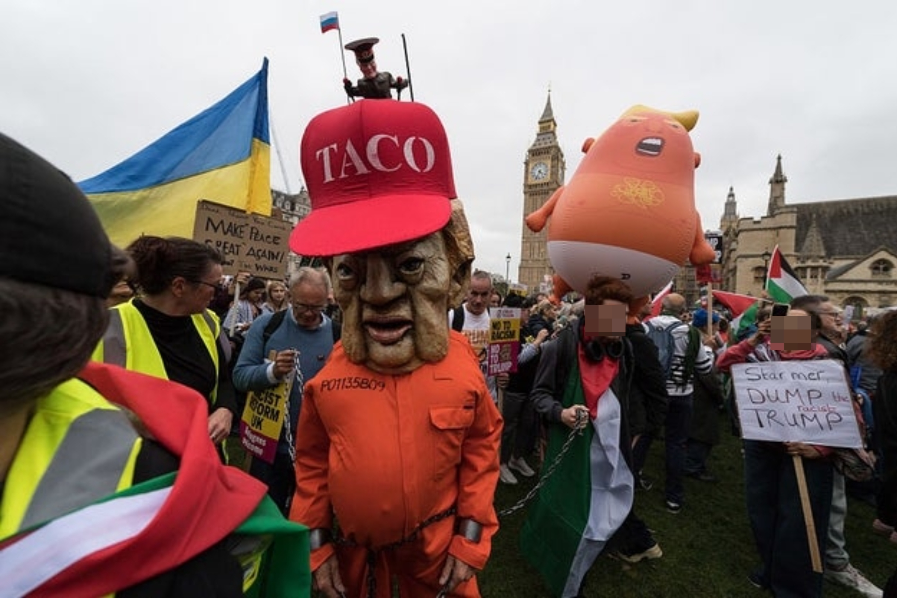 Demonstranter i London med bannere. Man har på seg et gigantisk karikaturhode, og det er en stor oppblåsbar luftball i bakgrunnen