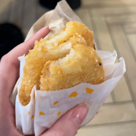 Close-up of a manus holding a flaky, fried pastry successful a insubstantial wrapper