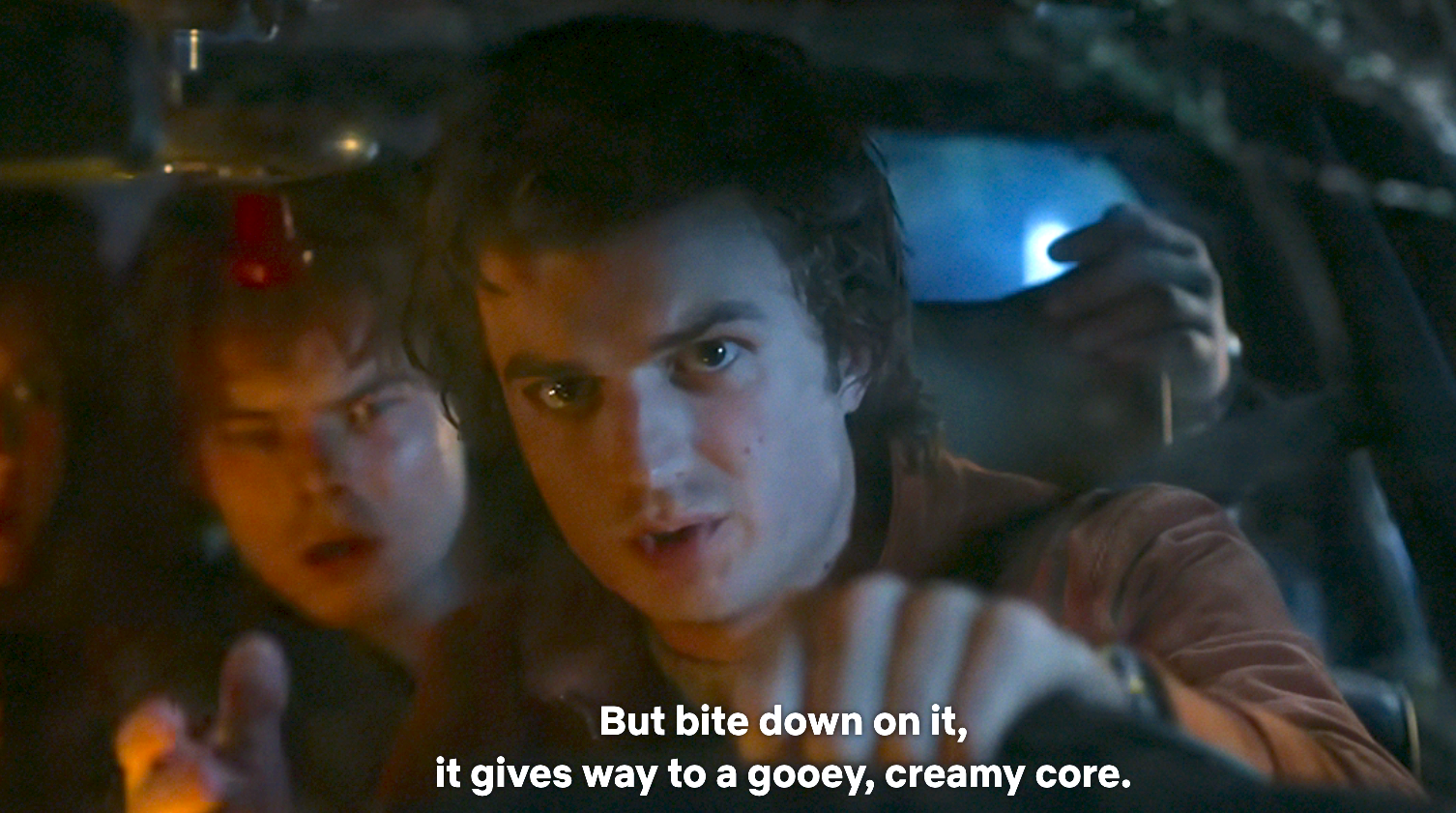 Group of people in a car at night, with one person driving, focused, and caption reads: "But bite down on it, it gives way to a gooey, creamy core."