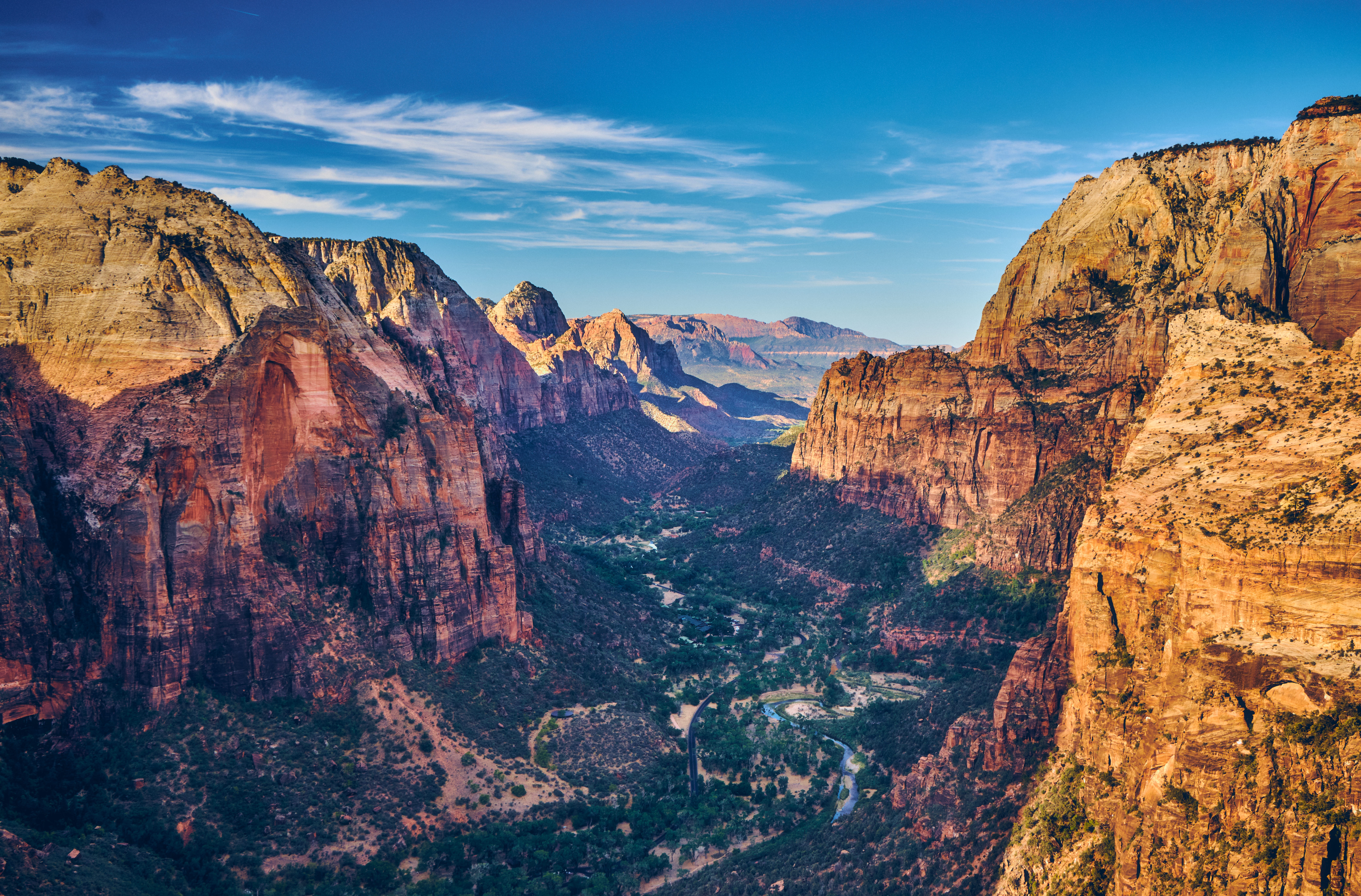 Luftfoto av et stort canyonlandskap med ruvende klipper og en svingete grønn dal nedenfor, som viser frem naturlige fjellformasjoner