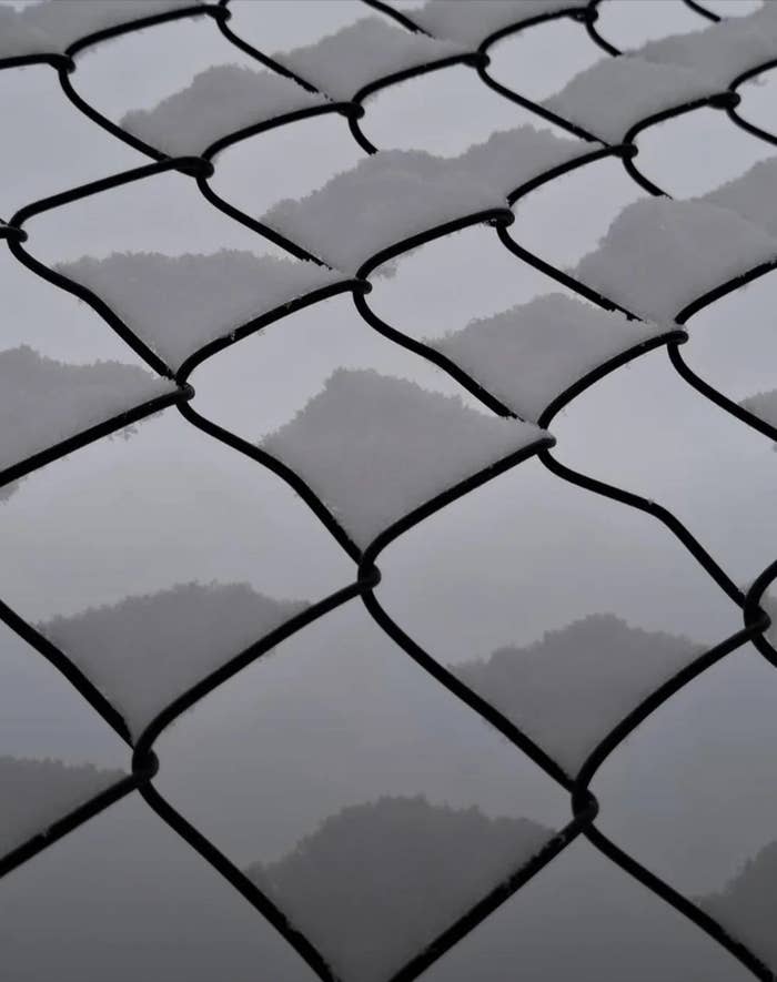 Close-up of a chain-link obstruction   with snowfall  connected  the wires, creating a patterned texture