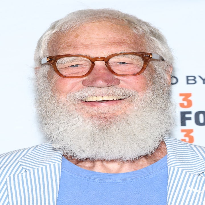 David Letterman with a beard and glasses, wearing a shirt and striped blazer at a public event