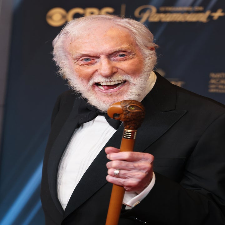 Dick Van Dyke in a tuxedo, holding a decorative cane, smiles broadly at a formal event