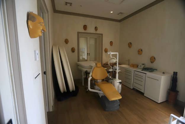 Dental bureau   with a attraction    chair, dental equipment, and respective  masks connected  the walls for decoration. Surfboards are propped successful  a corner