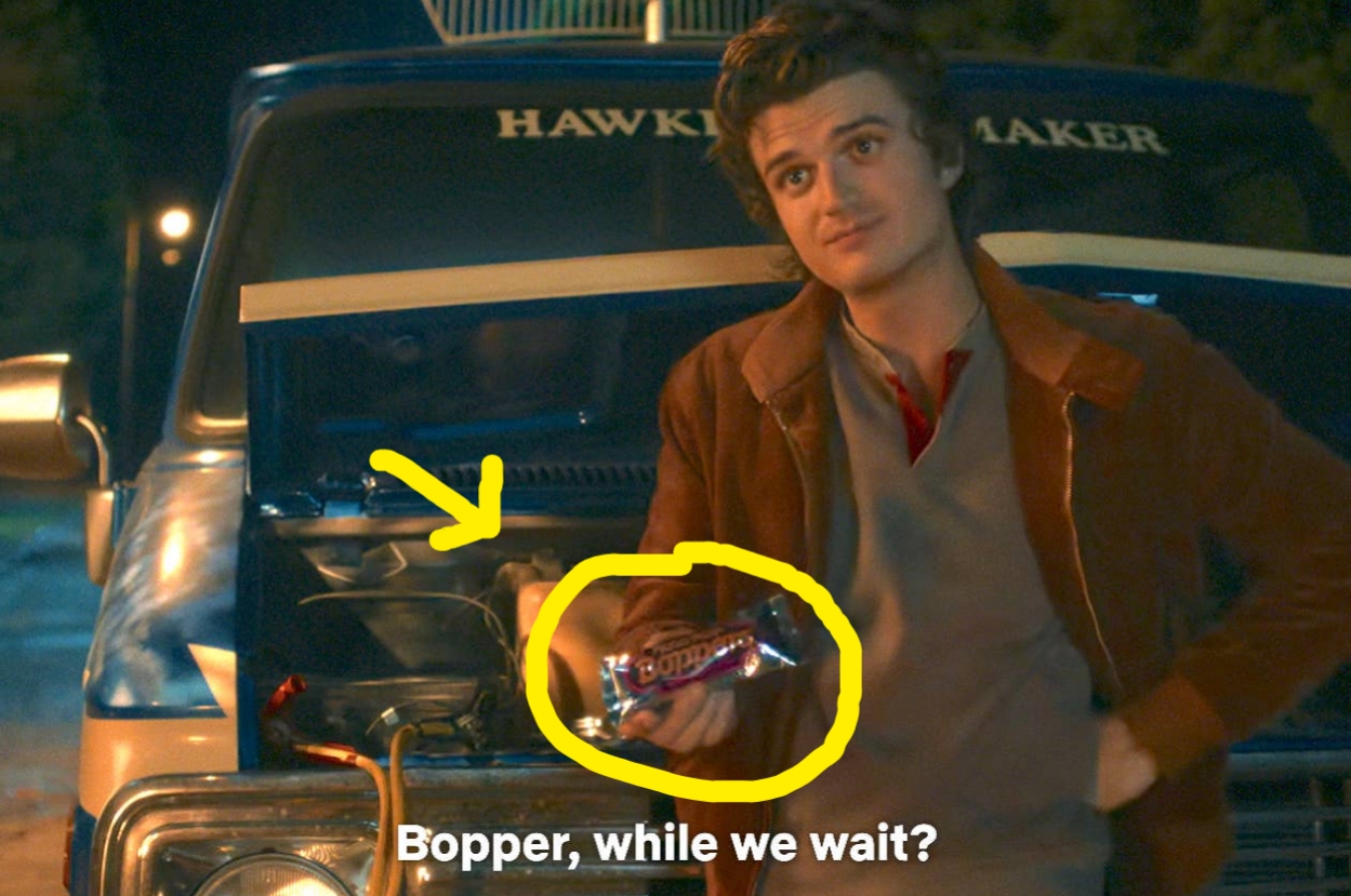 Person in casual jacket holds a Boppa package next to a car engine. Subtitle reads: "Bopper, while we wait?"