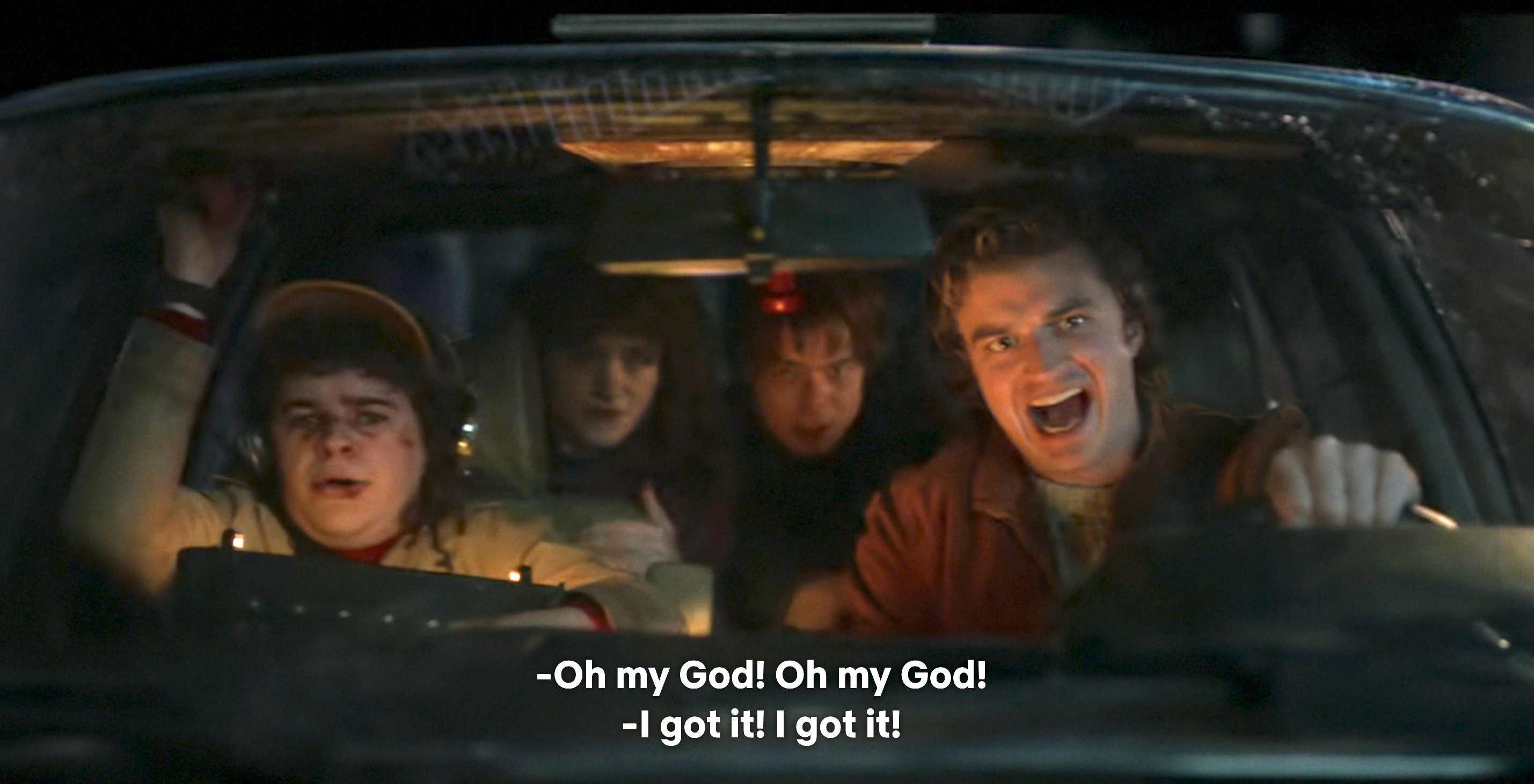 Four people in a car look alarmed. The driver shouts "I got it! I got it!" while another exclaims "Oh my God! Oh my God!"