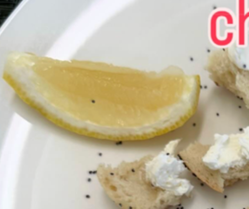 Lemon wedge on plate with poppy seed-topped bread bites and cream cheese