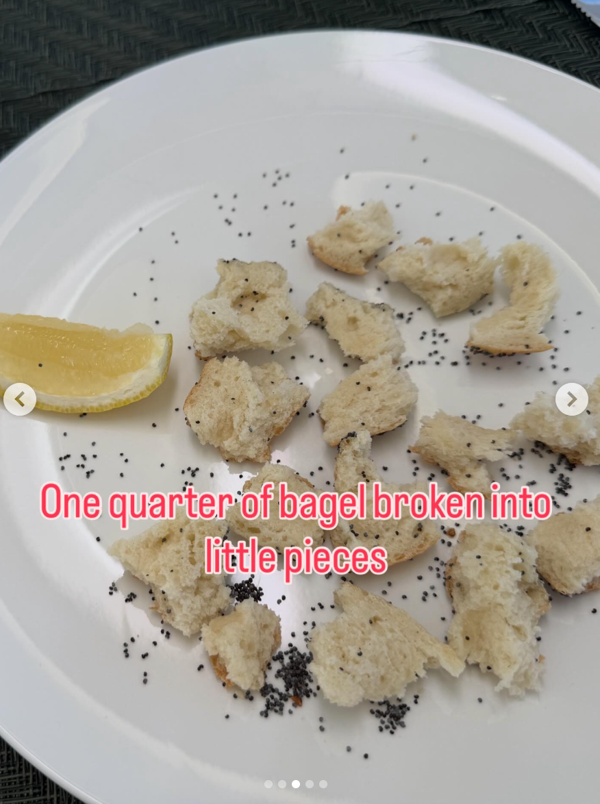 Quarter of a bagel in pieces with poppy seeds on plate, lemon wedge on side. Text reads, "One quarter of bagel broken into little pieces."