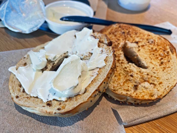 A toasted bagel dispersed  with pick  food  connected  a napkin, with a tiny  instrumentality  of pick  food  and a weapon  nearby