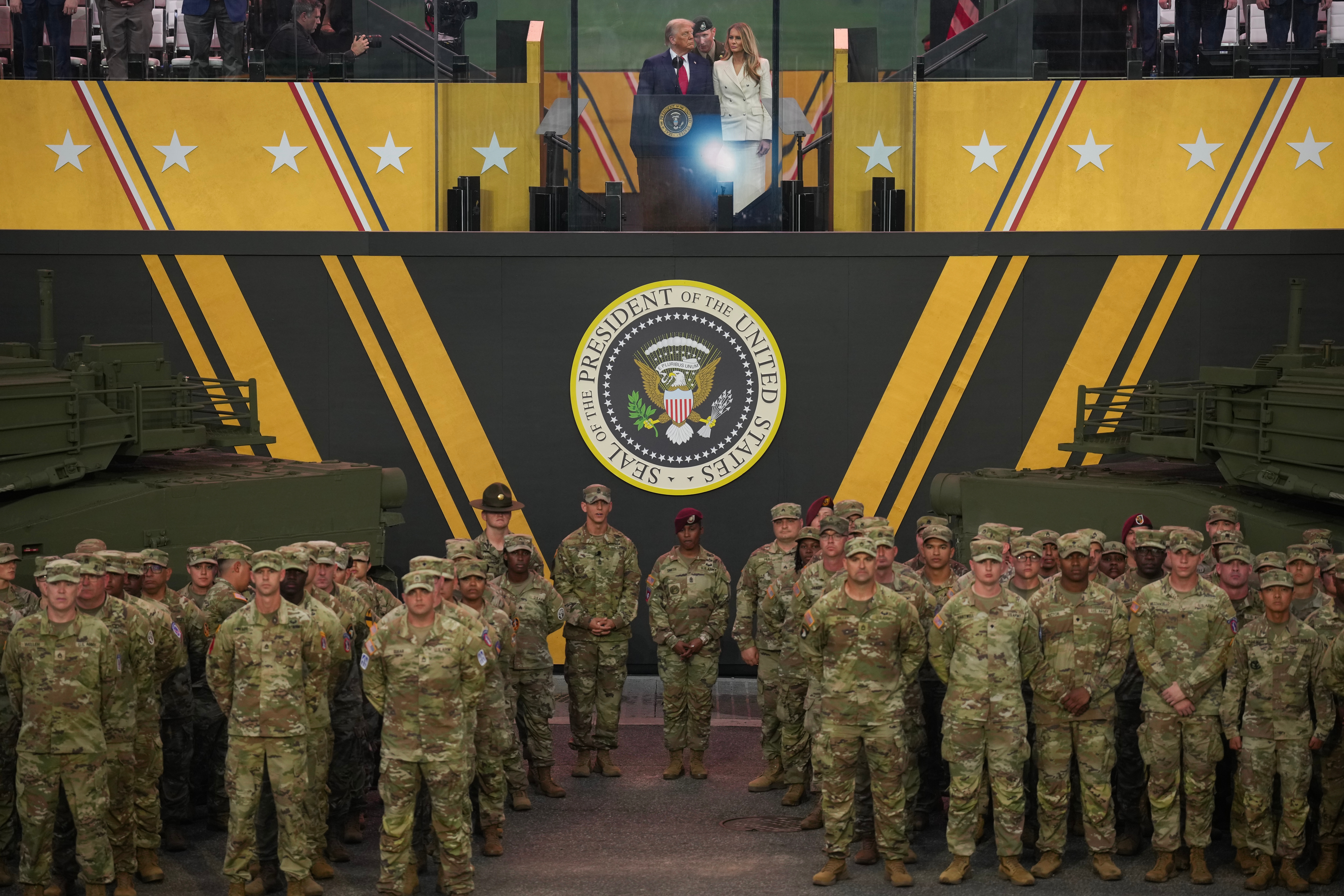 En gruppe militært personell i uniform står på oppmerksomhet. En foredragsholder står på et podium med presidentseglet