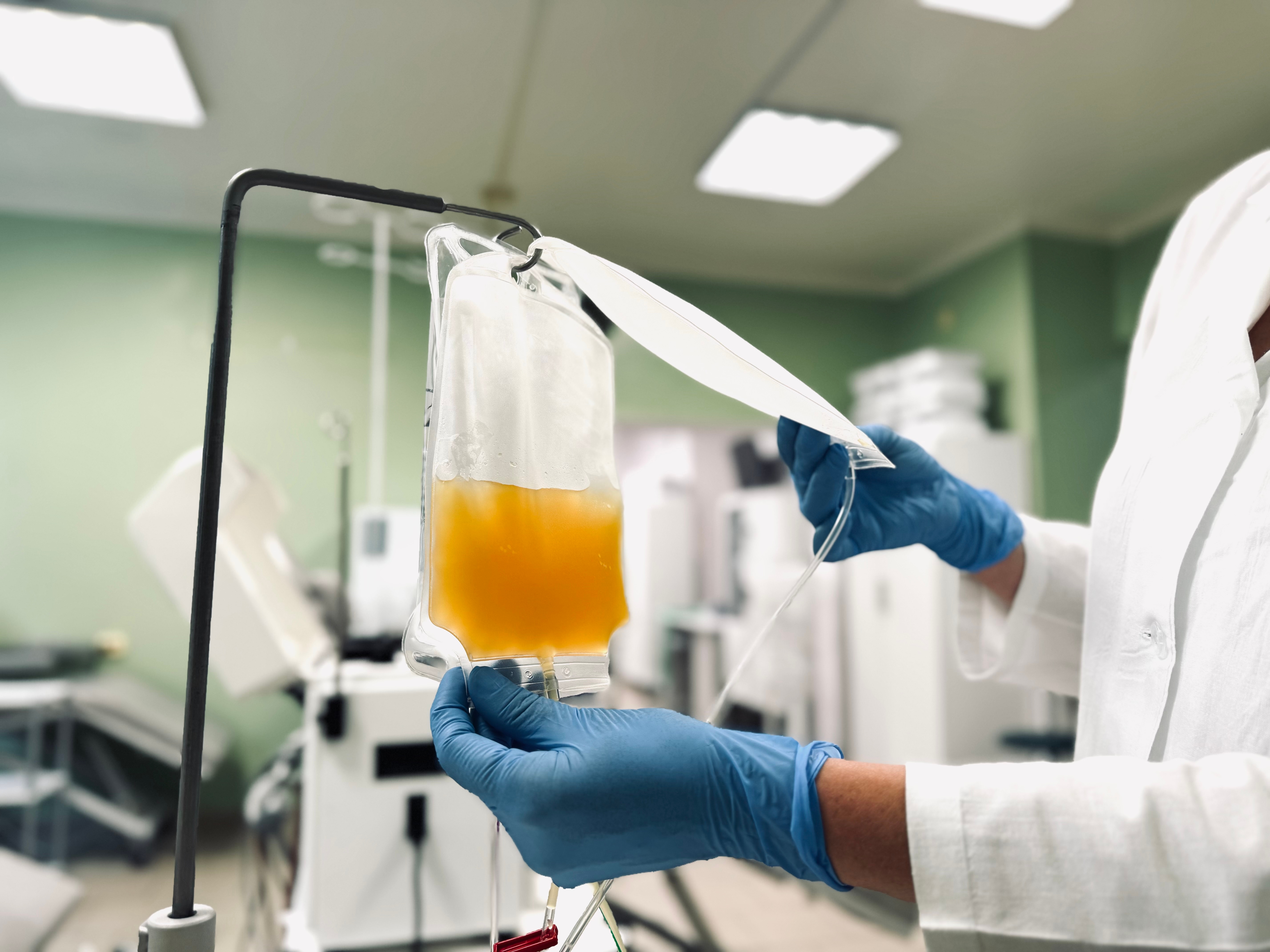 Person successful laboratory overgarment and gloves adjusting an IV container of yellowish fluid successful a aesculapian setting