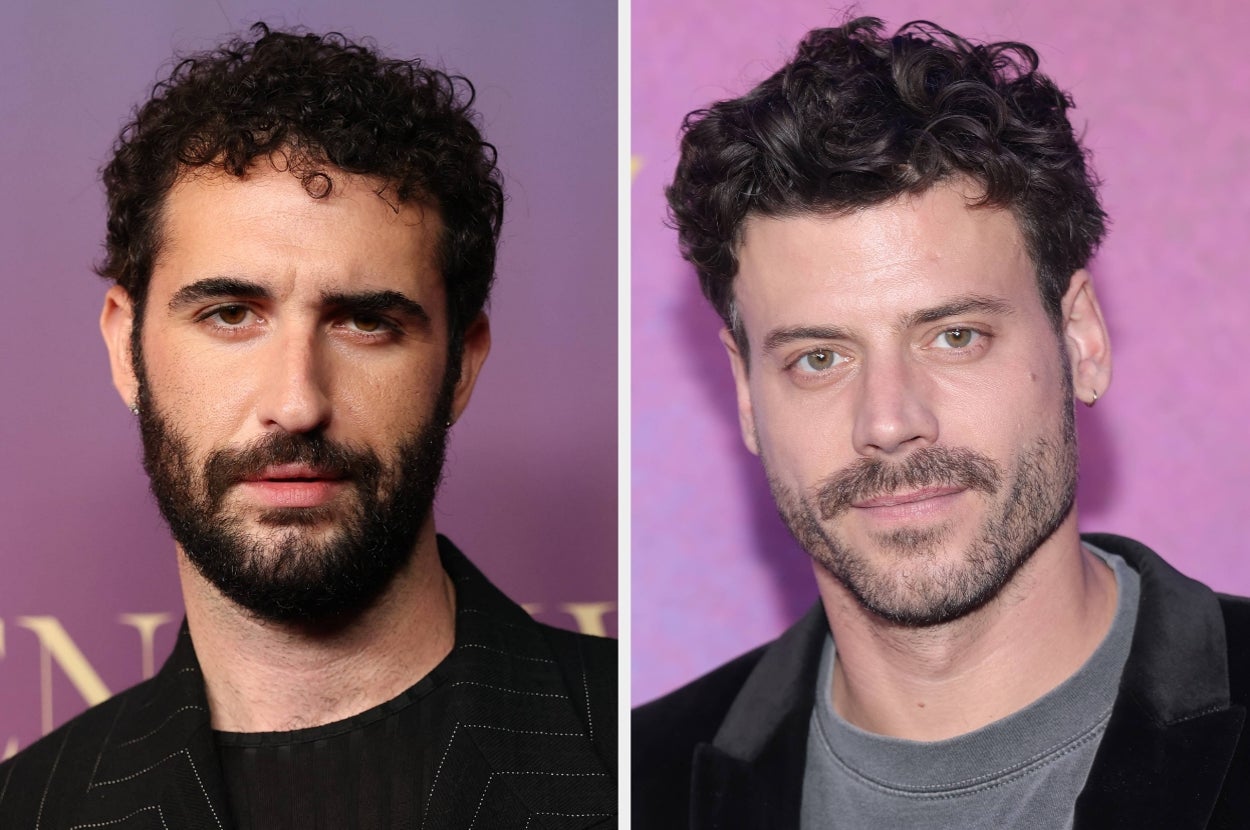 Two men with short, curly hair pose at an event. Both wear dark jackets and have facial hair, standing against a purple backdrop