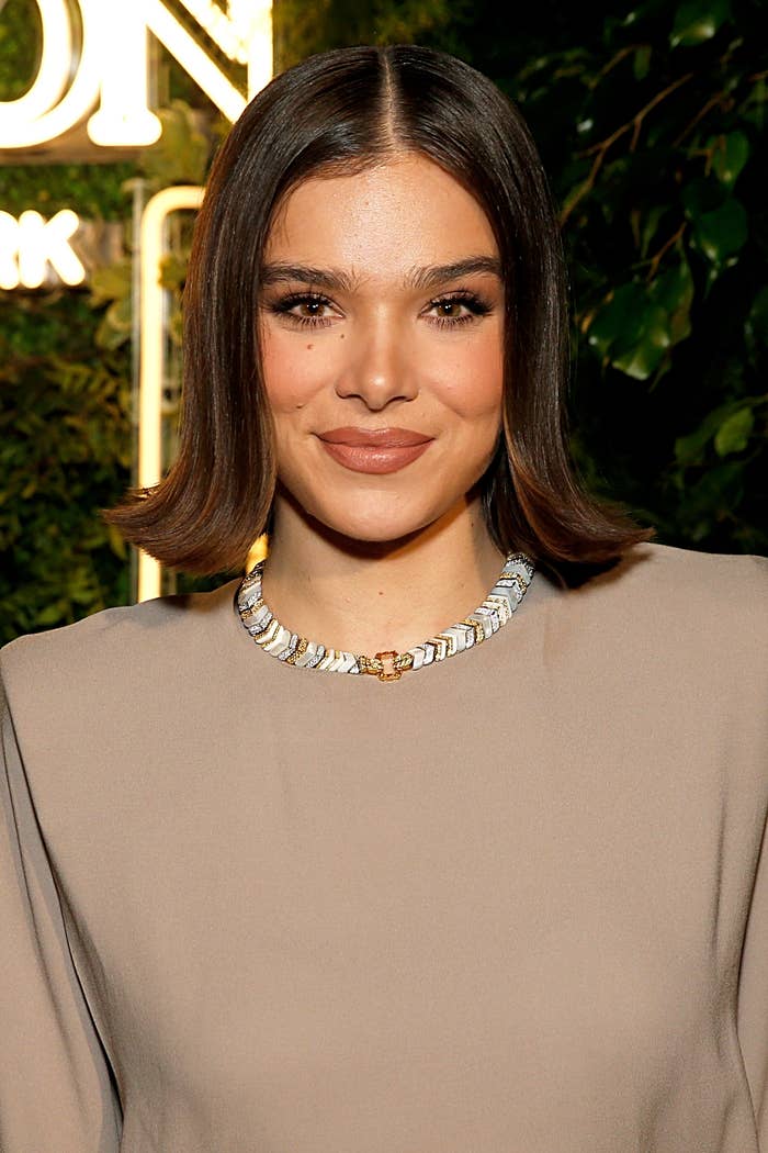 Hailee Steinfeld with shoulder-length hairsbreadth  wearing a elemental  elegant formal  with a beaded necklace, smiling astatine  an event