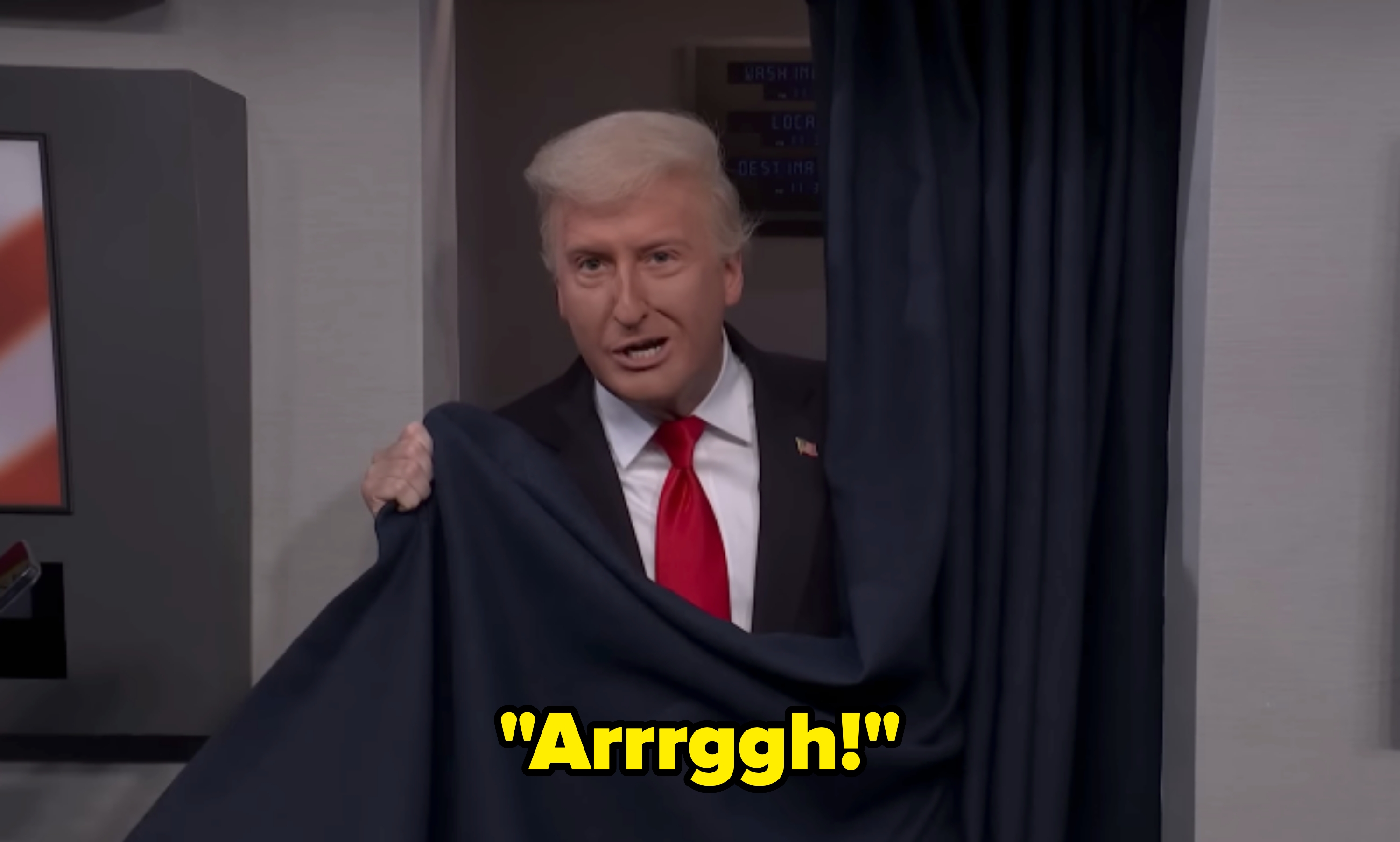 Person med stylet hår og dress titter lekent bak en gardin