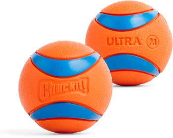 Two orangish Chuckit! Ultra canine balls with bluish stripes and embossed text, positioned broadside by side