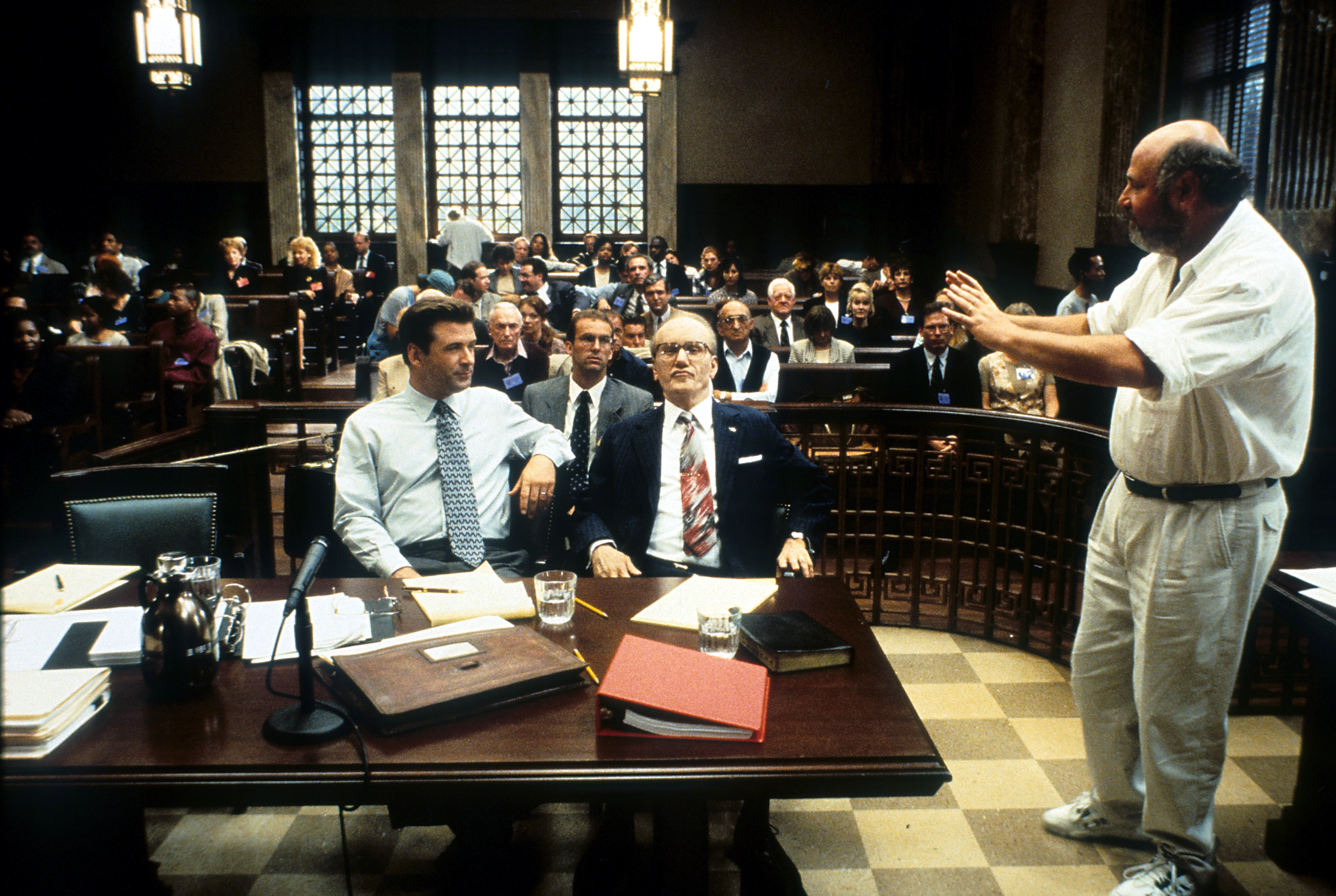A movie manager gives instructions to actors successful a engaged courtroom set, showcasing a melodramatic country being filmed