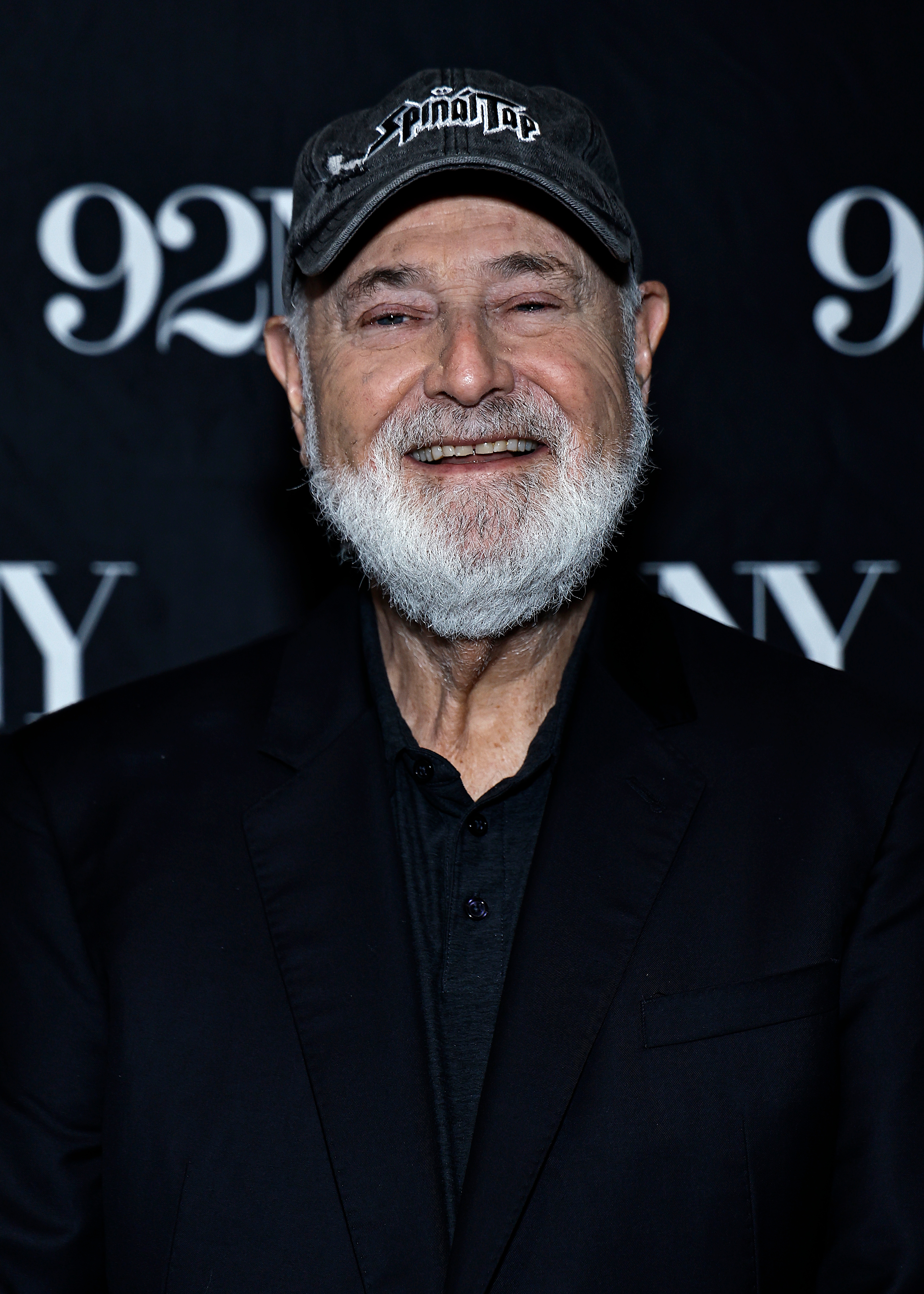 Rob Reiner with a beard wearing a headdress  and acheronian  overgarment   stands successful  beforehand   of a backdrop with "92Y" text