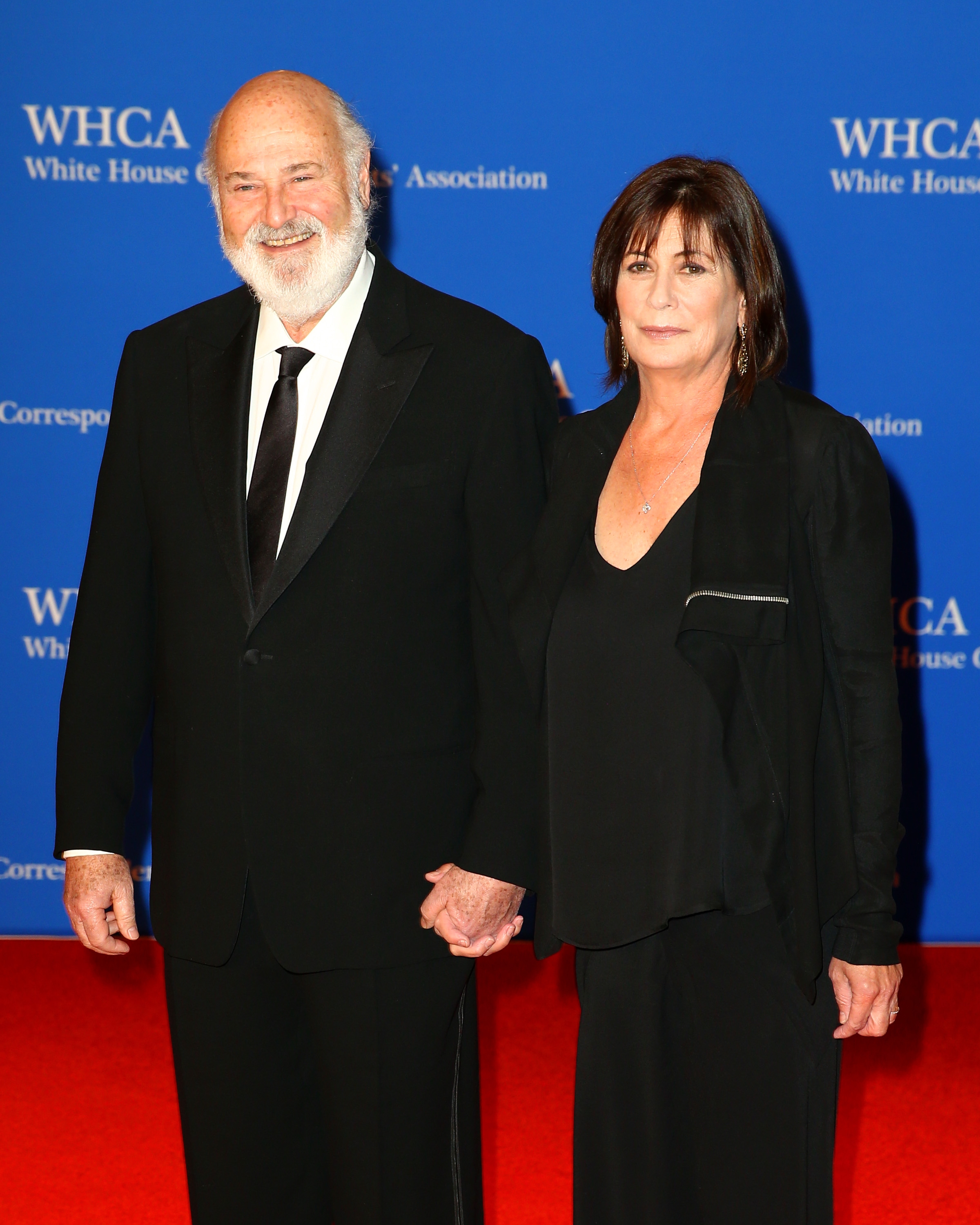 Rob Reiner and Michele Singer holding hands astatine  an event, dressed successful  ceremonial  attire. The antheral   wears a suit   and tie, the pistillate   wears a achromatic  formal  and jacket