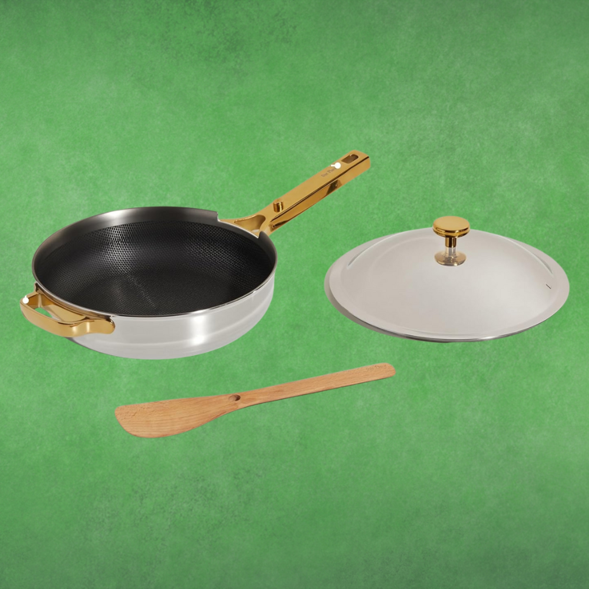 Frying cookware  with a aureate  handle, matching lid, and woody  spatula connected  a greenish  background