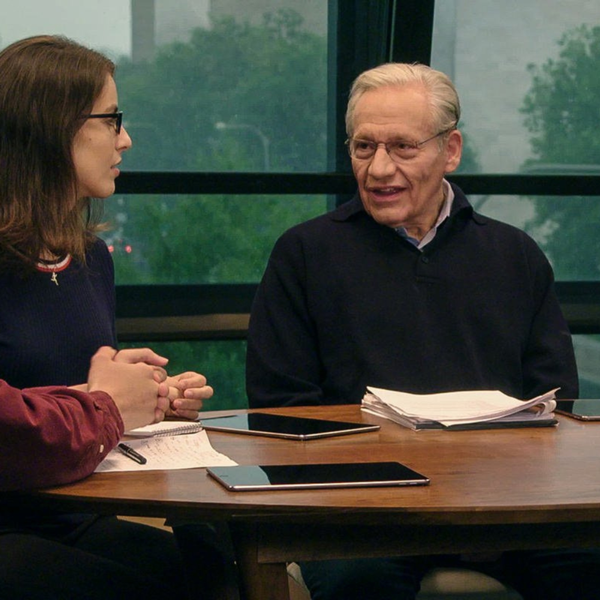 Two radical   sitting astatine  a array  with notepads and tablets, engaged successful  discussion, successful  a casual setting