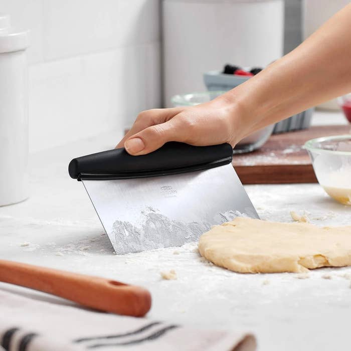 Hand utilizing a pastry scraper to chopped  dough connected  a room  antagonistic  among baking tools and ingredients