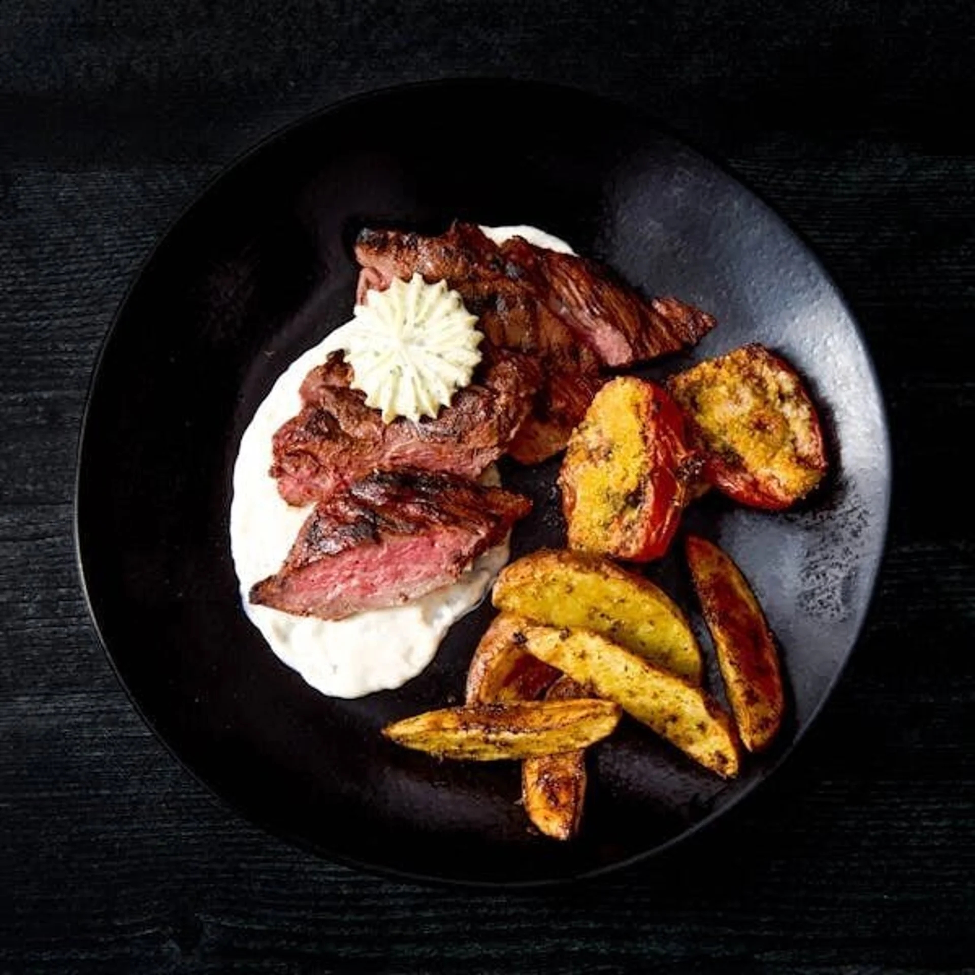 Plate of grilled steak with food  connected  mashed potatoes, served with roasted potatoes and grilled vegetables connected  a achromatic  plate