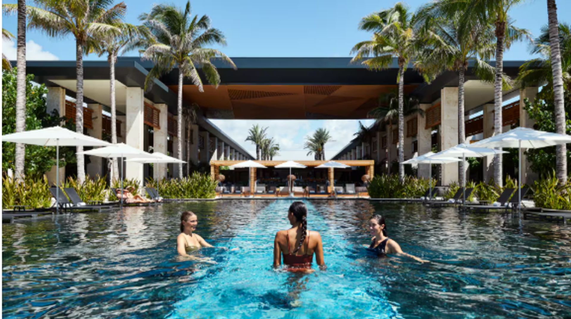 Three radical   unbend  successful  a luxurious edifice   excavation  surrounded by thenar  trees, prima   umbrellas, and lounge chairs, showcasing a tropical abrogation  setting