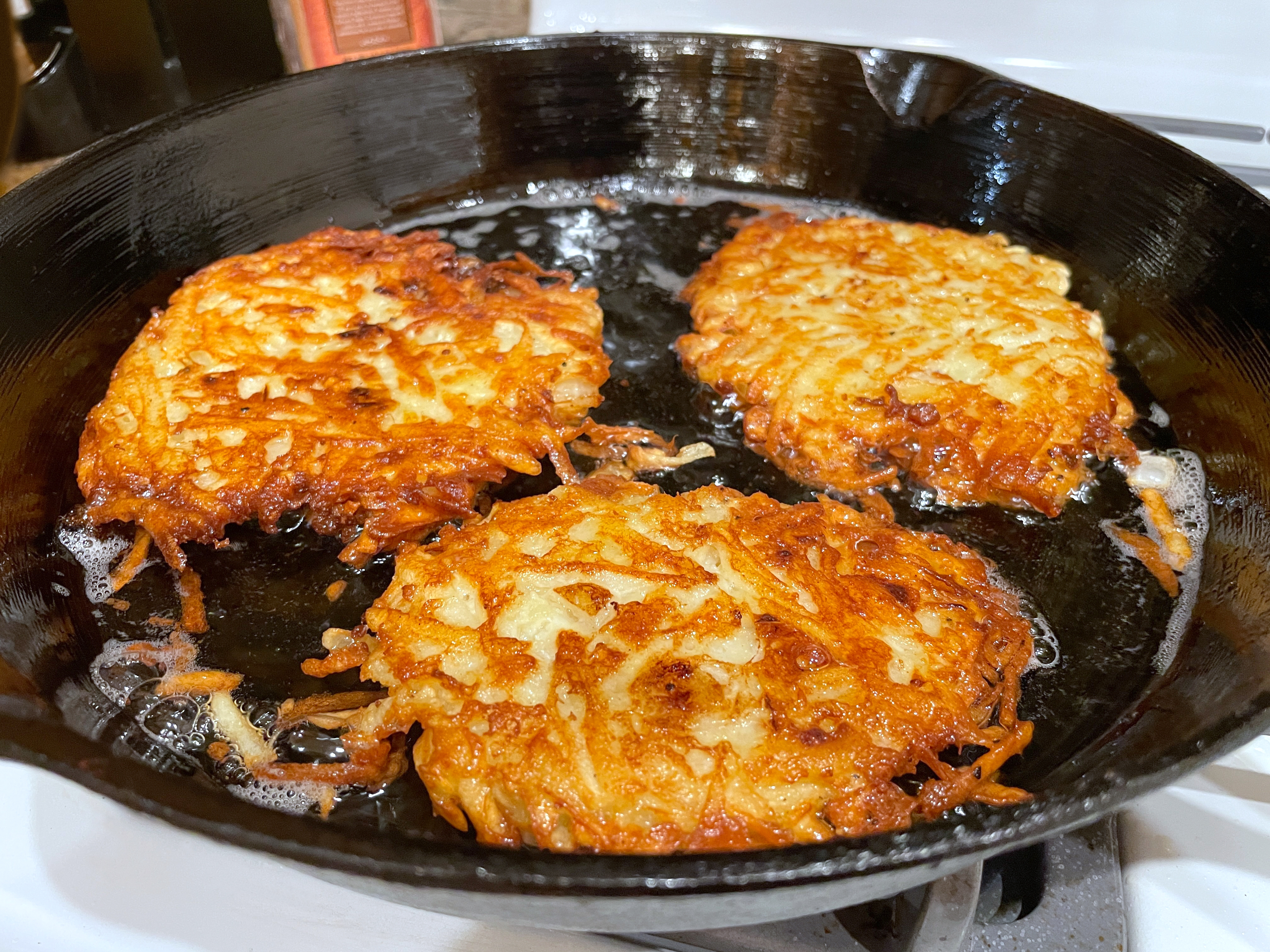 Three murphy latkes frying successful a formed robust skillet