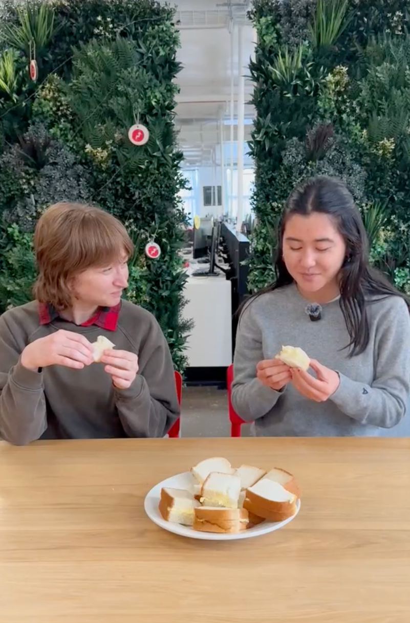 Two people sitting at a table with a plate of bread slices, tasting and enjoying the bread