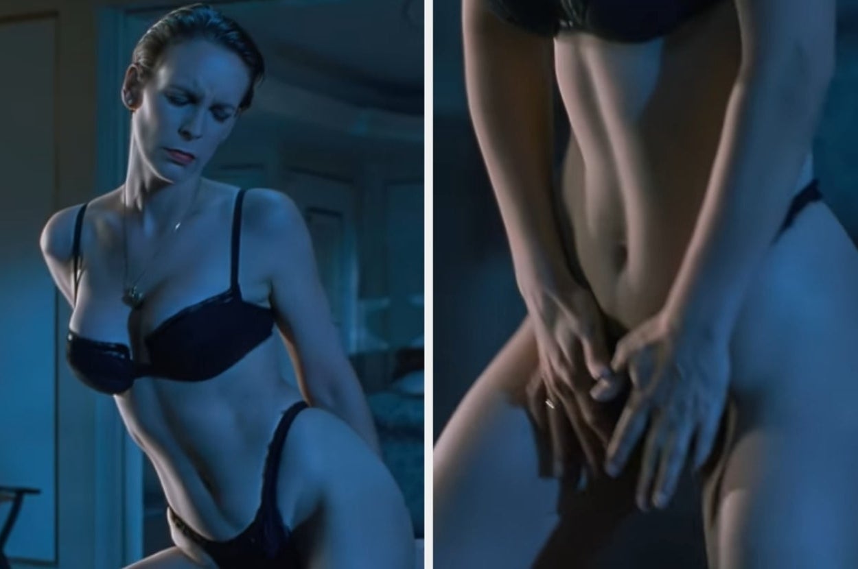 Person wearing a black bra and underwear, posing indoors in a dimly lit setting