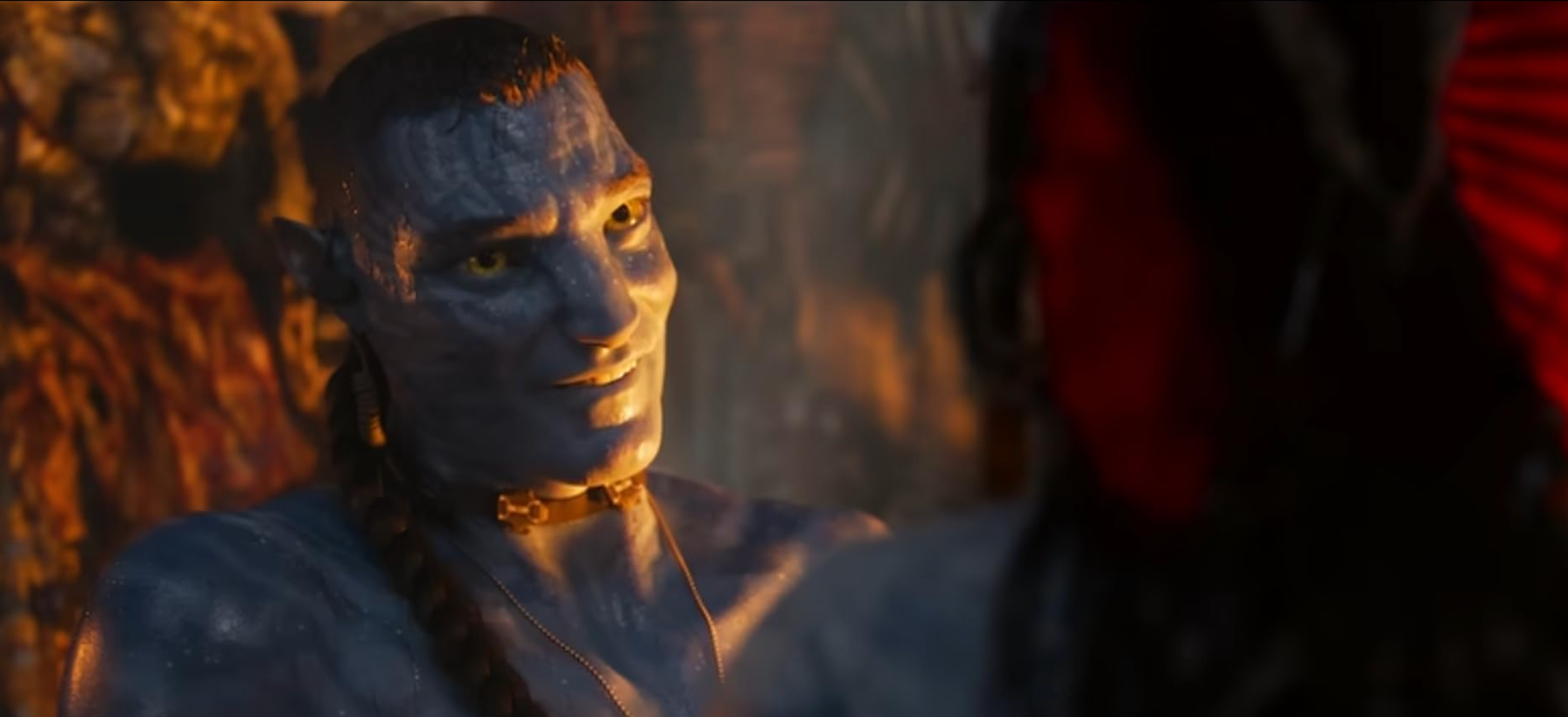 En scene fra en sci-fi-film med en datamaskingenerert stammekarakter med blå hud og flettet hår, smilende til en annen karakter