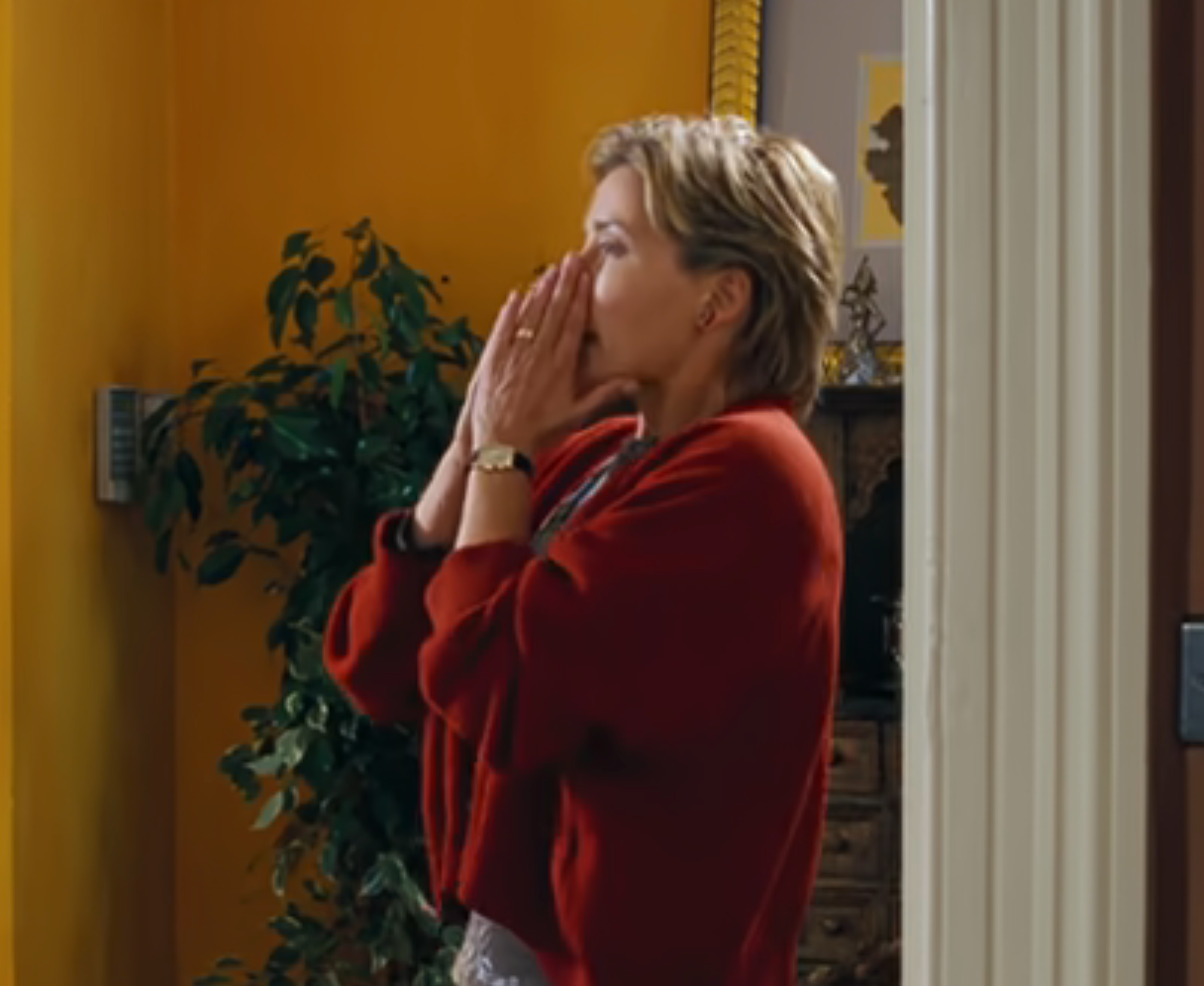 Person stands indoors, clasping hands implicit    rima  successful  evident  astonishment  oregon  concern, adjacent  to a potted plant