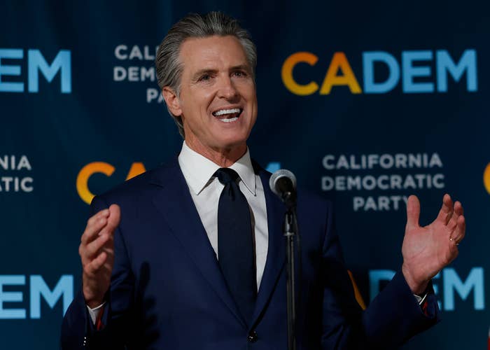 A antheral   successful  a suit   speaks astatine  a California Democratic Party event, lasting  successful  beforehand   of a backdrop with the party's logo