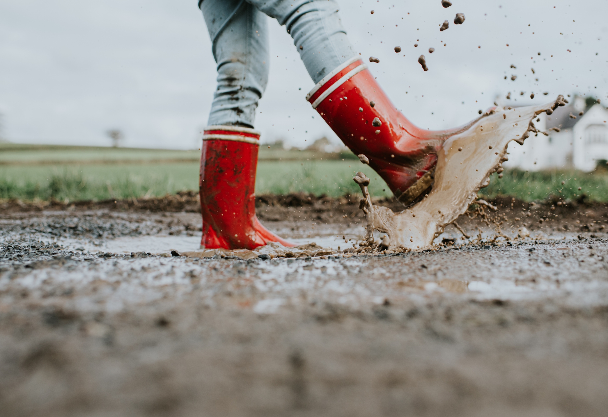 Child successful reddish boots splashes energetically successful a muddy puddle outdoors, creating a fun, carefree moment