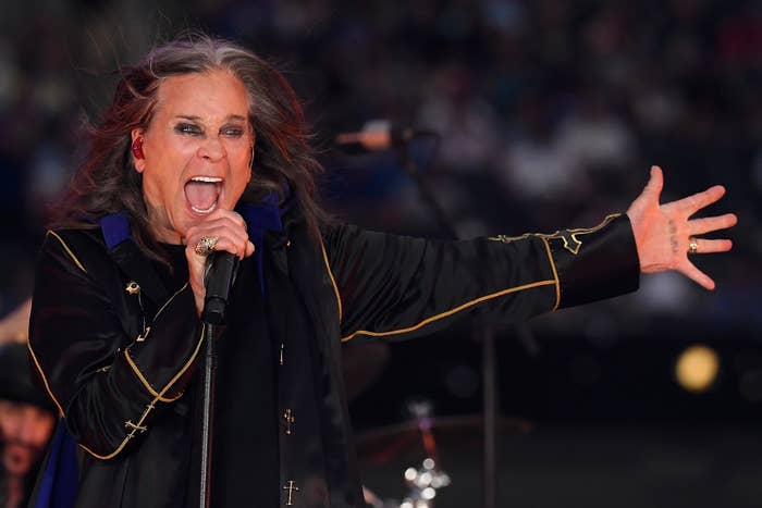 Ozzy Osbourne energetically sings into a microphone connected  stage, wearing a dark, agelong  overgarment  with golden  trim, and a ringing  connected  their hand