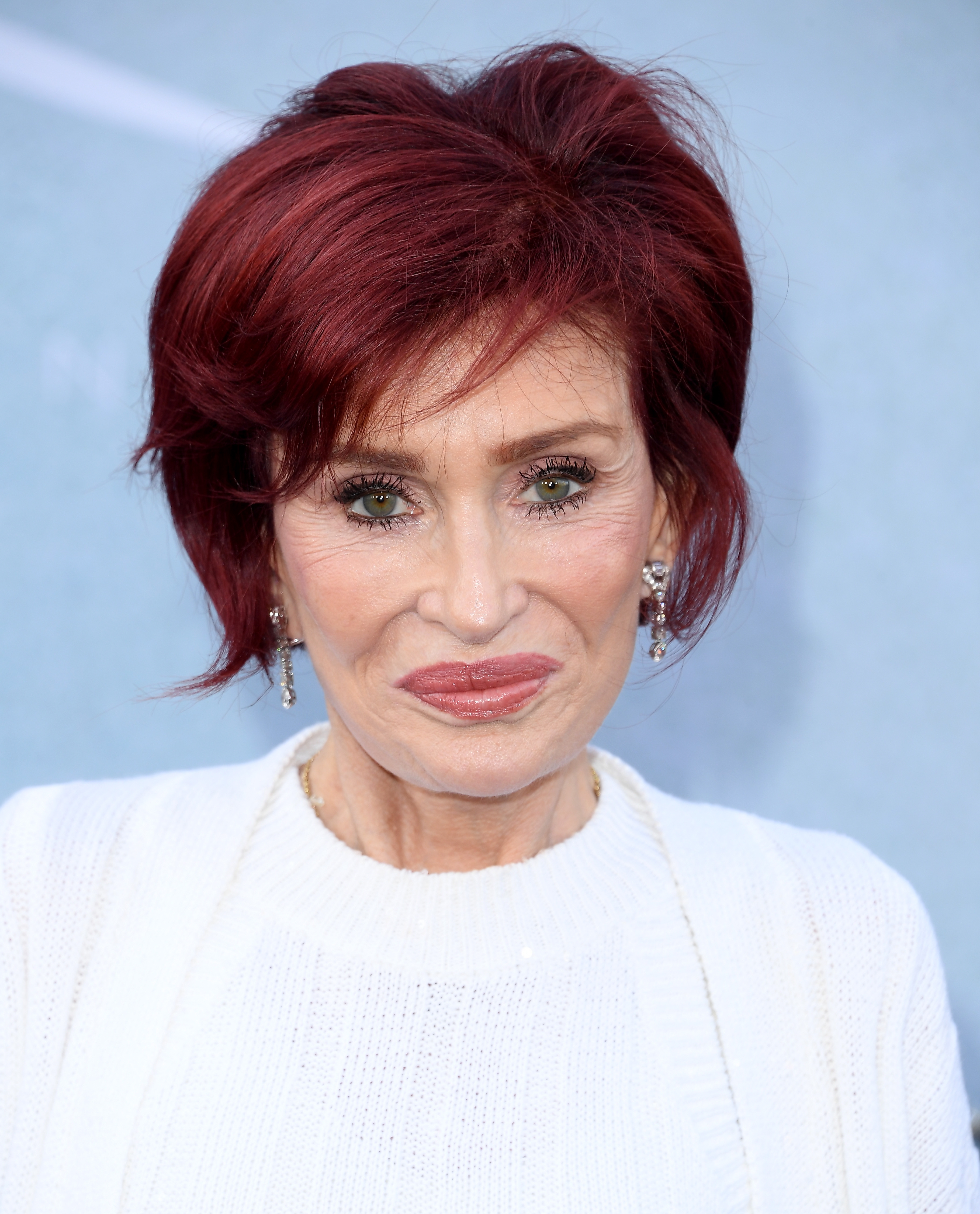 Sharon Osbourne with abbreviated  hairsbreadth  and a achromatic  outfit, looking astatine  the camera