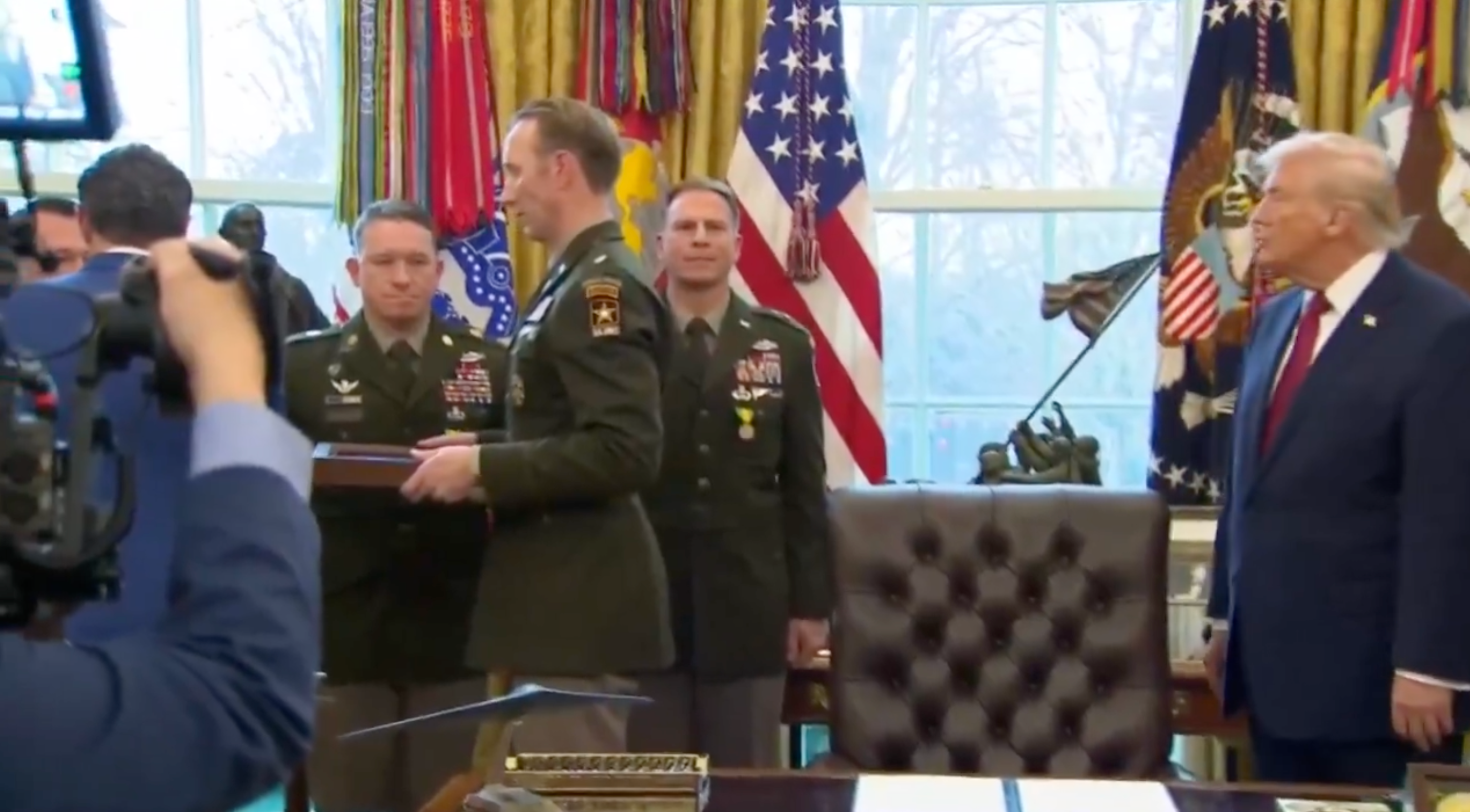 A radical of subject officers basal with a nationalist fig successful an bureau setting, facing a camera crew. American flags are disposable successful the background