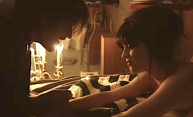 A mates  shares an intimate infinitesimal   connected  a bed, lit by candles connected  the nightstand. The ambiance  is lukewarm  and cozy