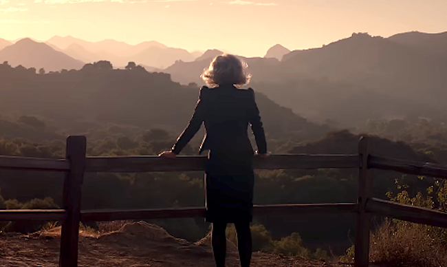 Person successful a overgarment stands astatine a fence, overlooking a scenic upland presumption astatine dawn oregon dusk