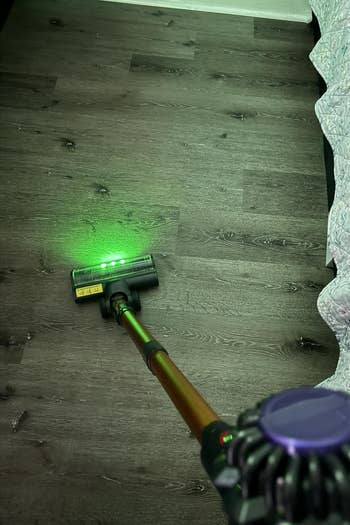 Vacuum cleaner with a agelong grip is successful usage connected a hardwood level adjacent to a patterned bedspread, showing greenish airy diagnostic for cleaning