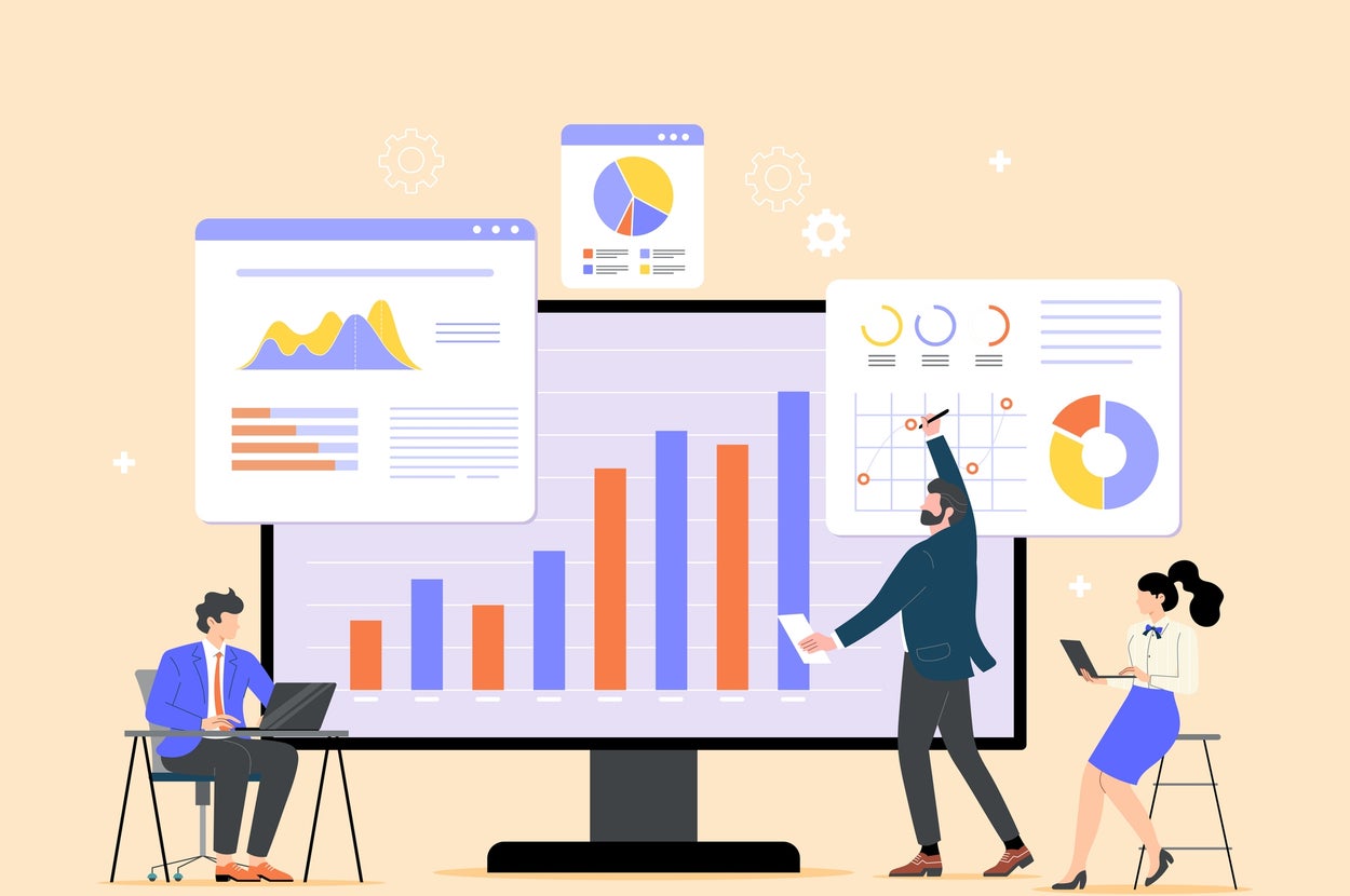 デスクでラップトップを使用する2人と、大画面の前でグラフを指す人のビジネスチーム。