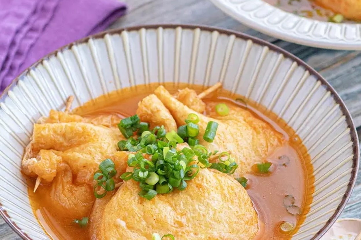 おでんの一種であるがんもどきが、出汁の中でネギと共に盛り付けられた料理。シンプルで美味しそうです。