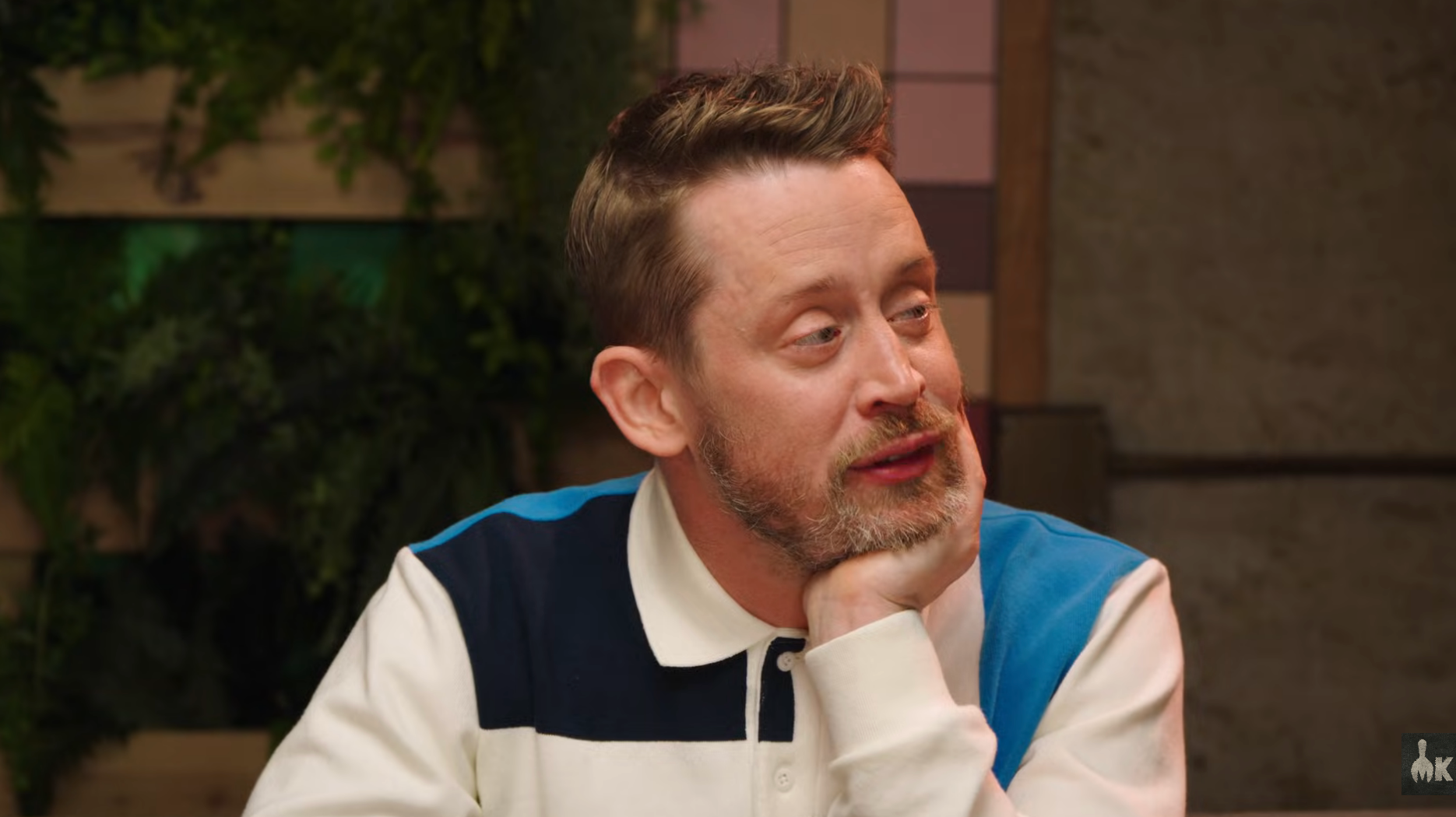 A idiosyncratic   with abbreviated  hairsbreadth  and a beard sits astatine  a table, resting their caput  connected  their hand, wearing a casual achromatic  and bluish  collared shirt